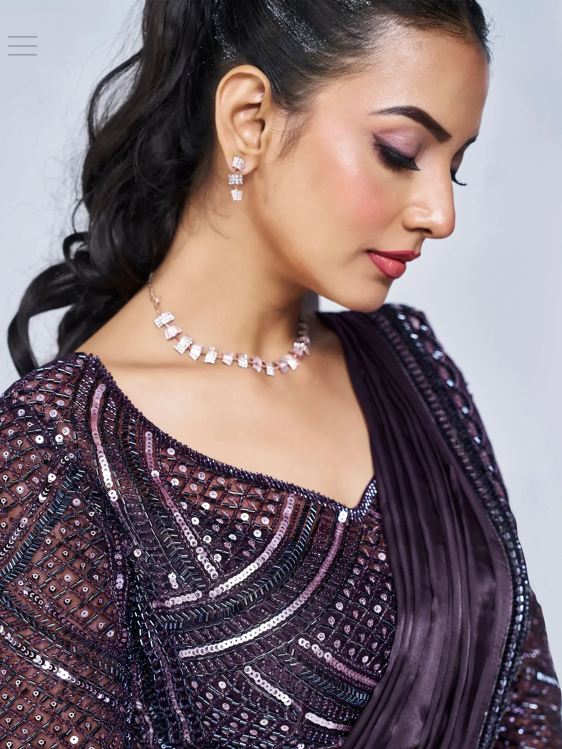 Elegant woman in purple sequined ethnic gown with matching jewelry, perfect for Indian celebrations.