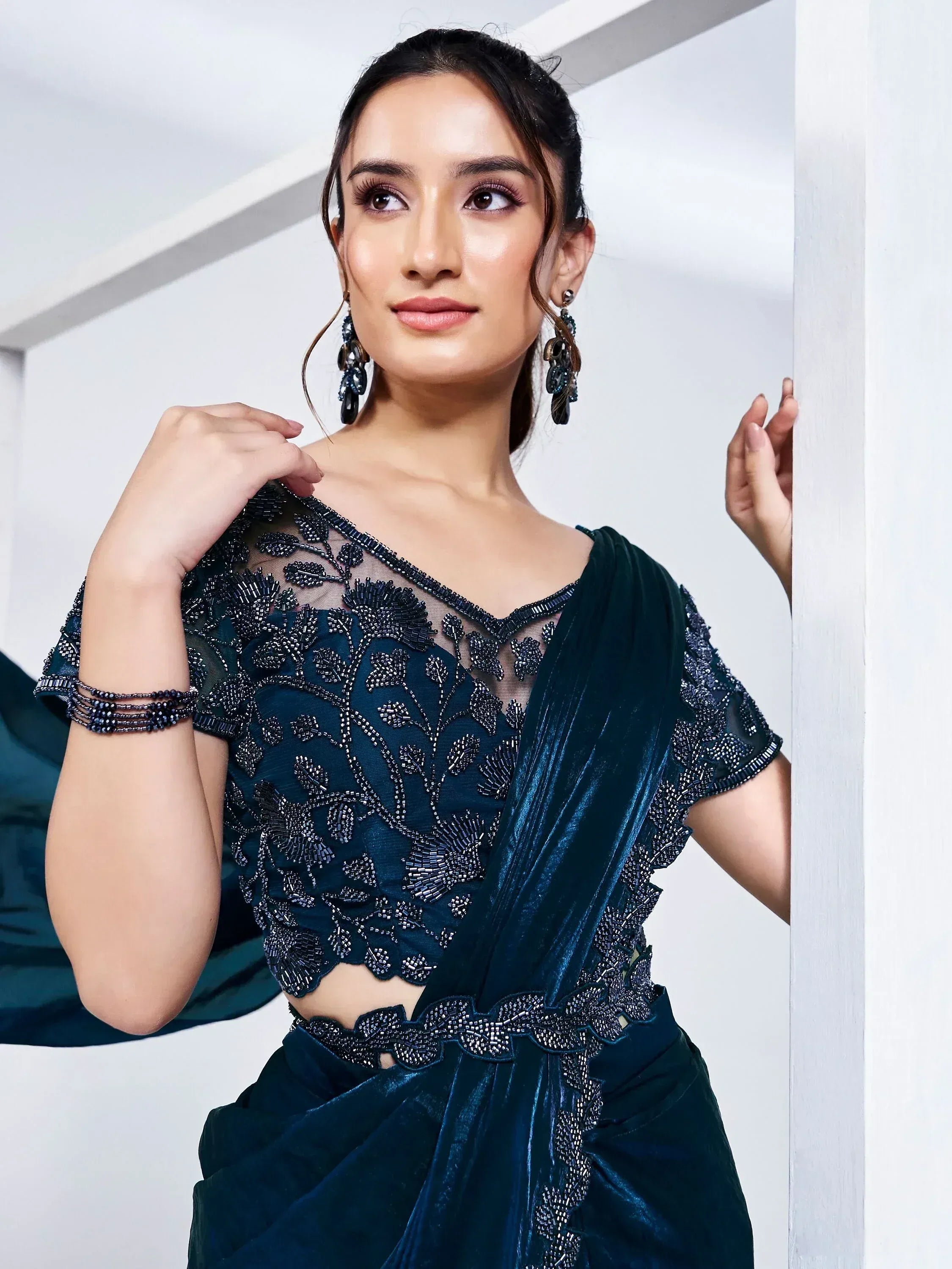 Elegant dark green velvet saree with intricate beadwork and sheer blouse, perfect for Indian ethnic occasions.