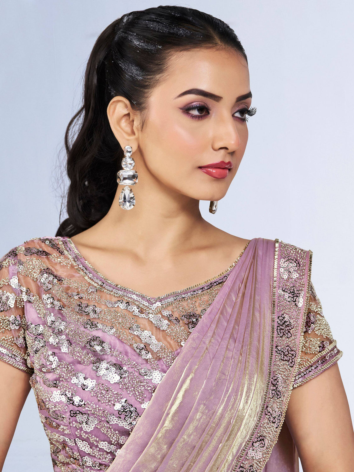 Elegant lavender saree with sequin embroidery and gold border, paired with statement crystal earrings.