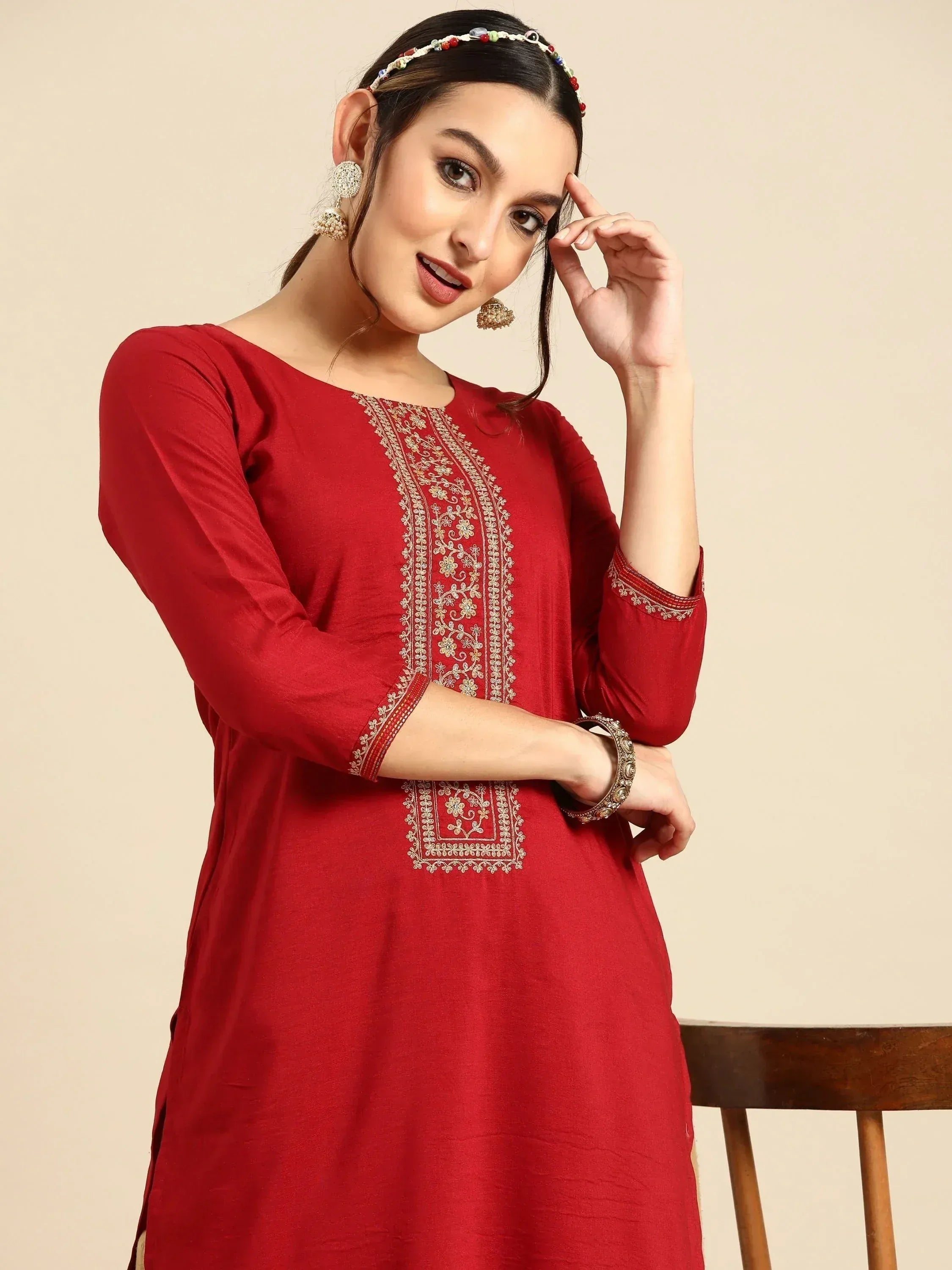 Red embroidered ethnic kurta with gold detailing, paired with traditional jewelry for festive occasions