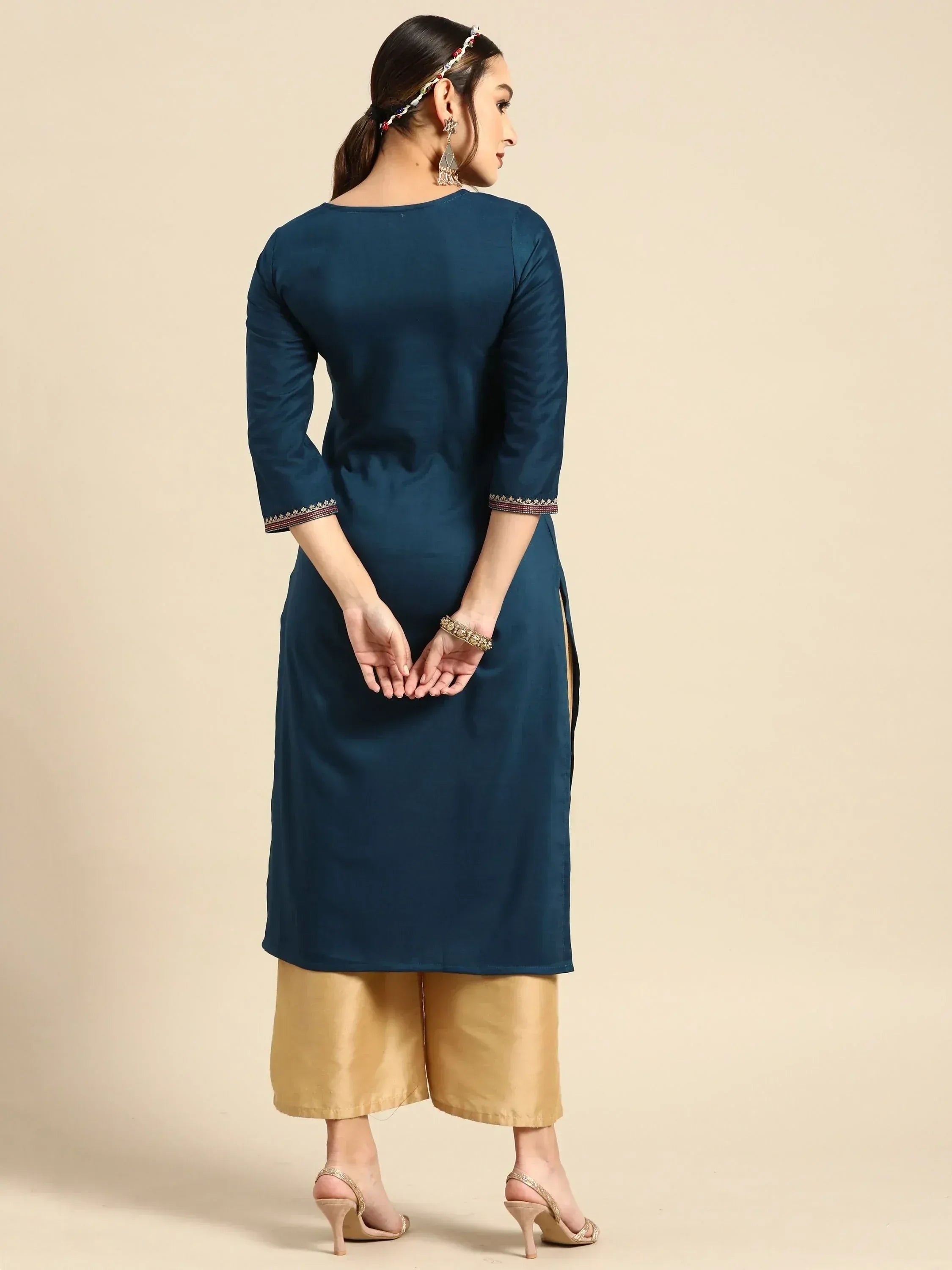 Woman in navy blue ethnic kurta with gold trim, paired with mustard palazzo pants and heels