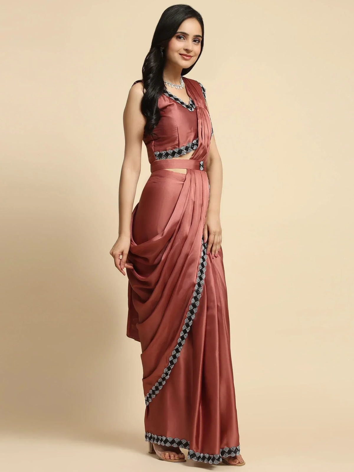 Dusty rose satin saree gown with black and white embroidered border, perfect for Indian ethnic occasions.