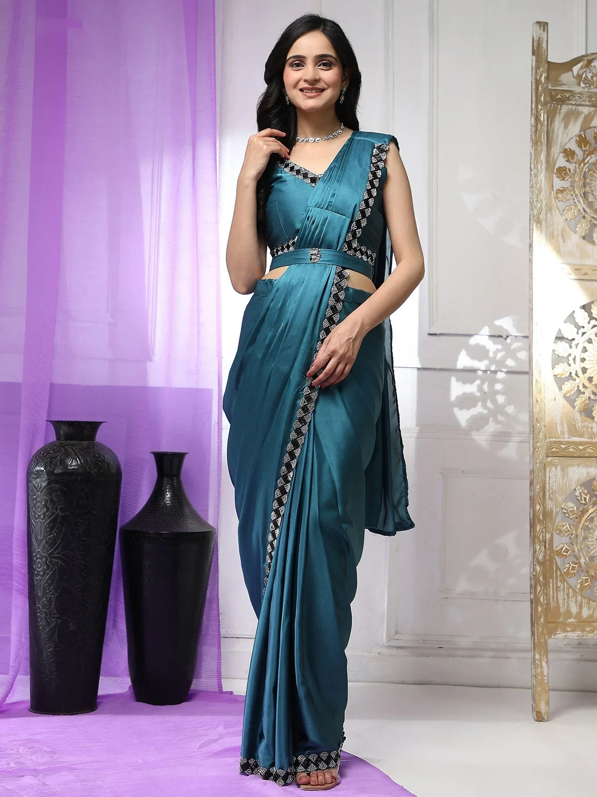 Teal satin saree with black and white embroidery, styled with a modern blouse and palazzo pants for ethnic wear.