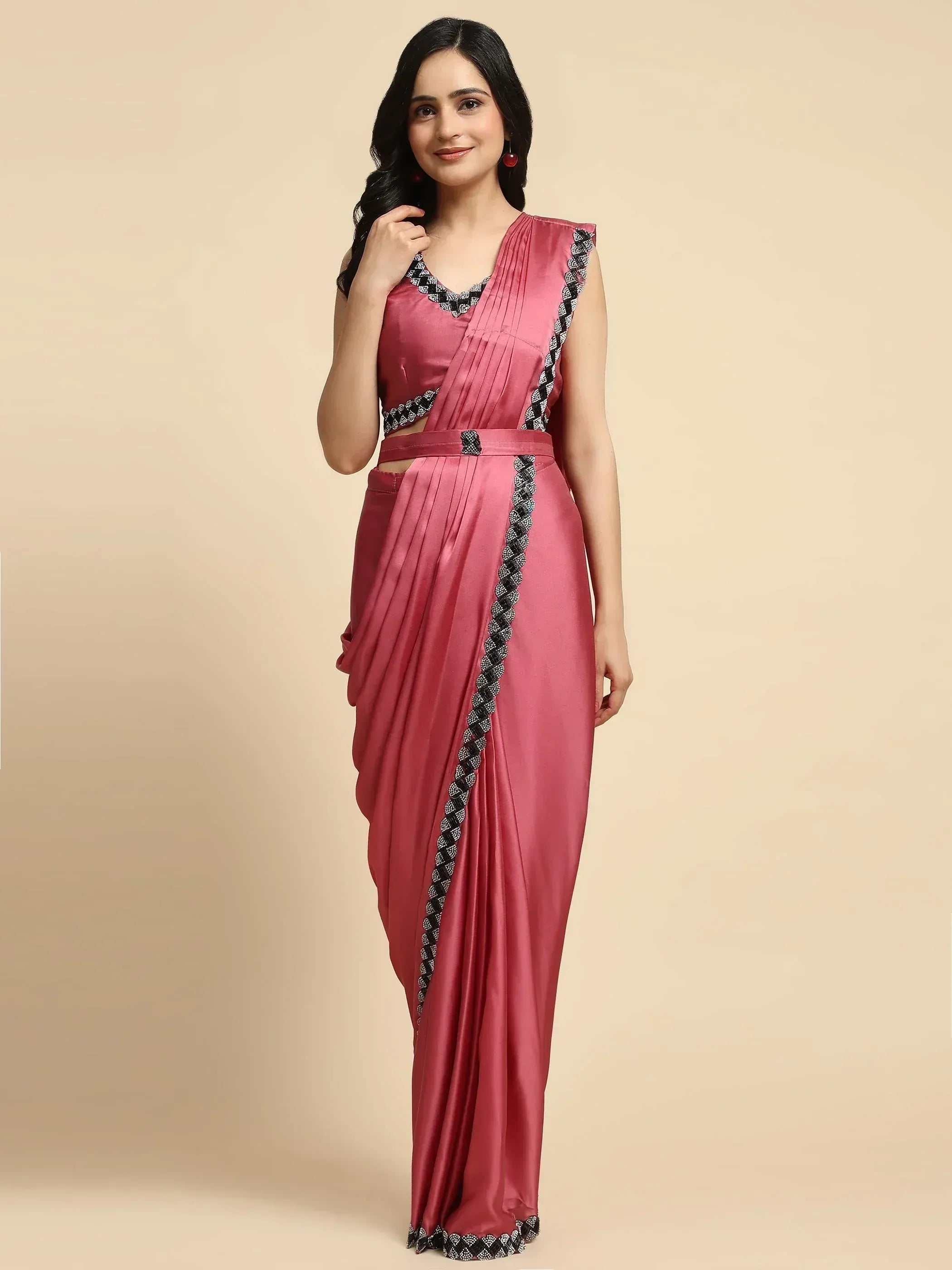 Pink satin saree with black and white embroidered border, pleated design, and sleeveless blouse for ethnic wear