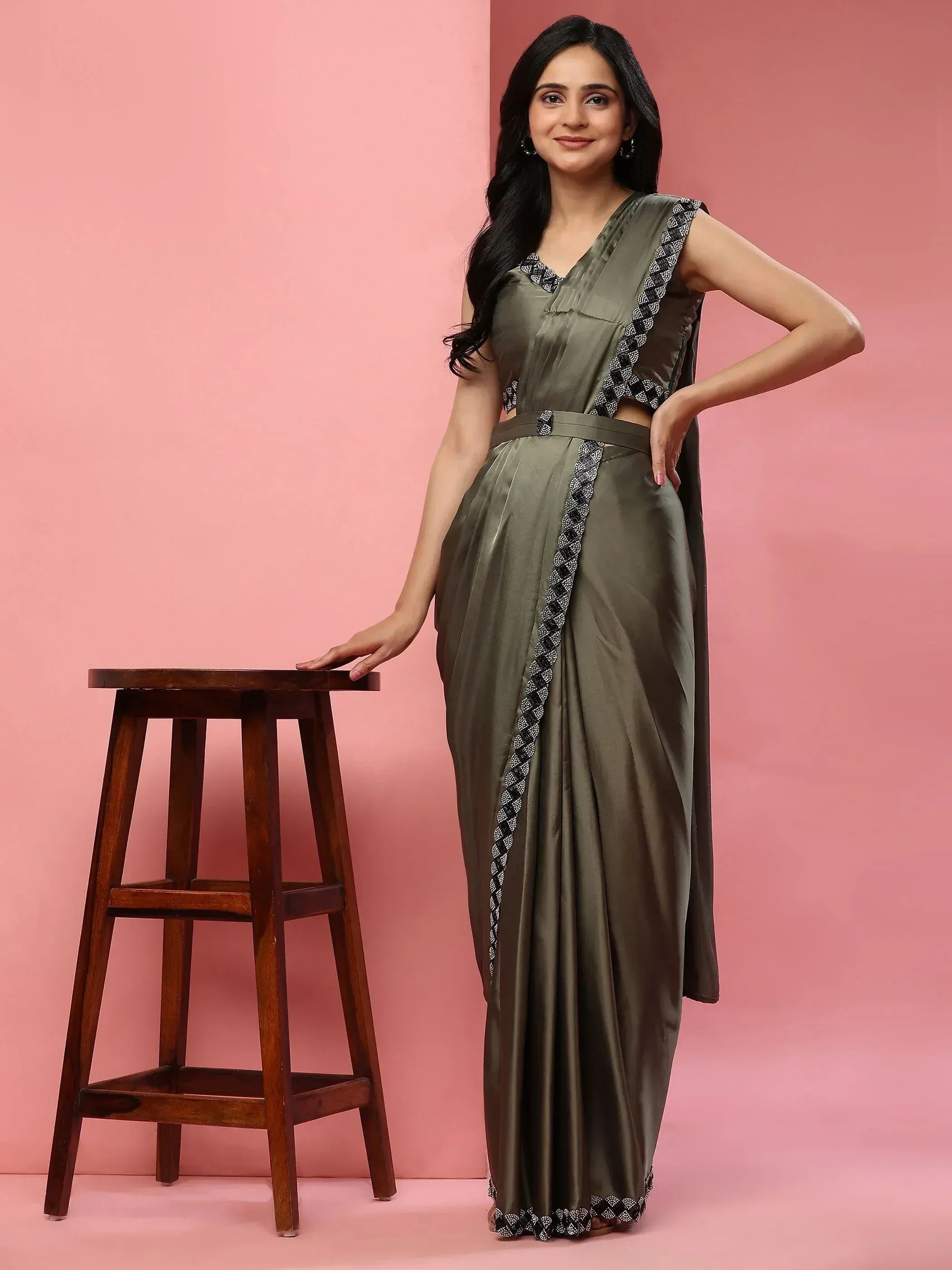 Olive green designer saree with black and white embroidery, styled with a sleeveless blouse and belt, perfect for ethnic occasions.