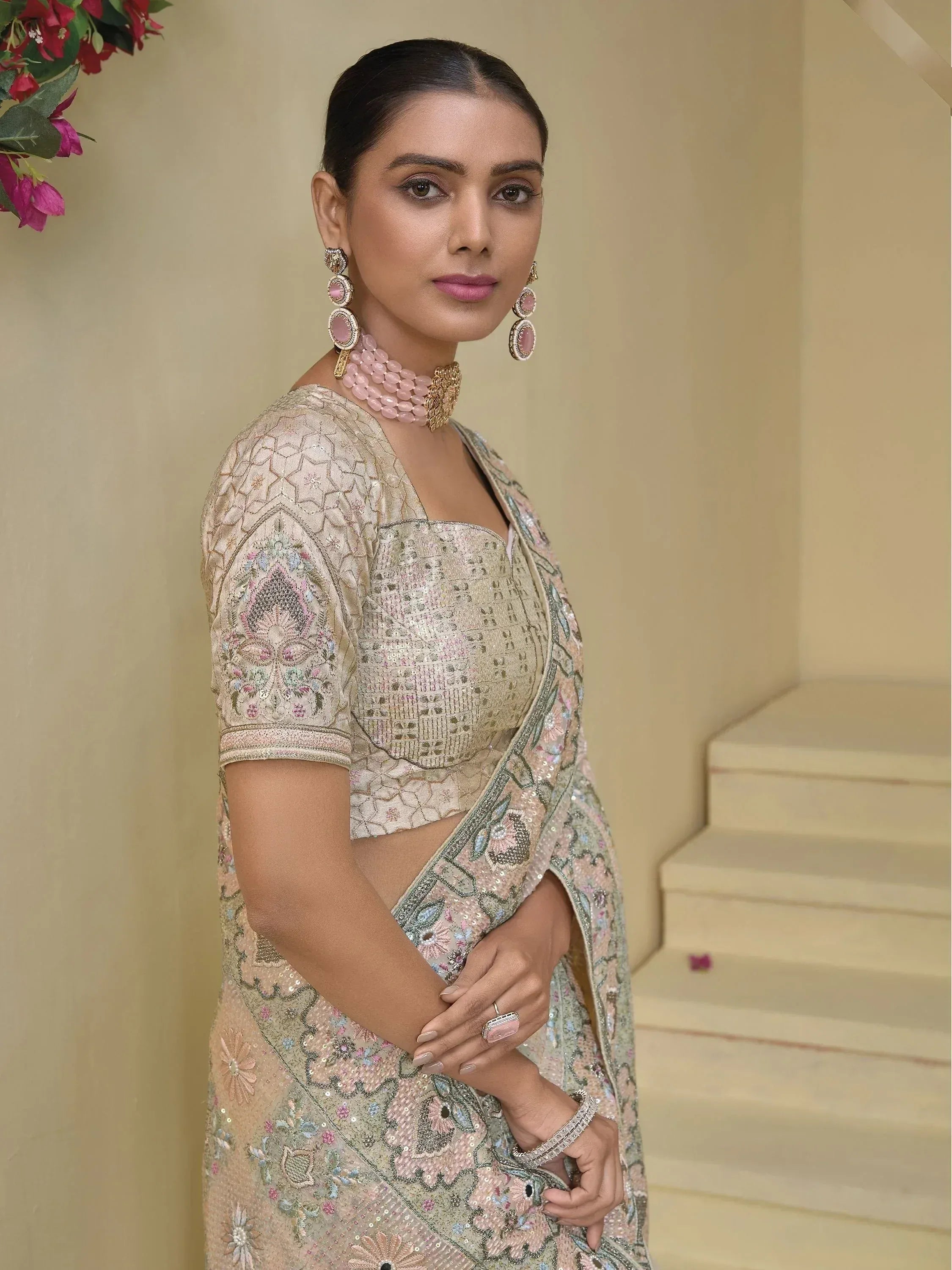 Elegant woman in embroidered designer saree with matching blouse and pink jewelry, perfect for Indian ethnic occasions.