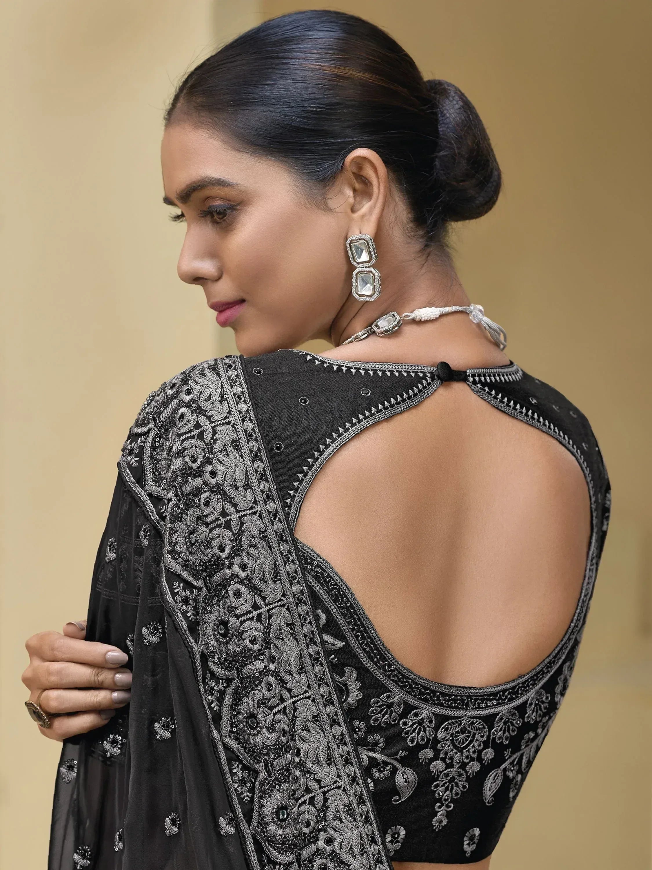 Black embroidered ethnic gown with open back, floral detailing, and statement earrings