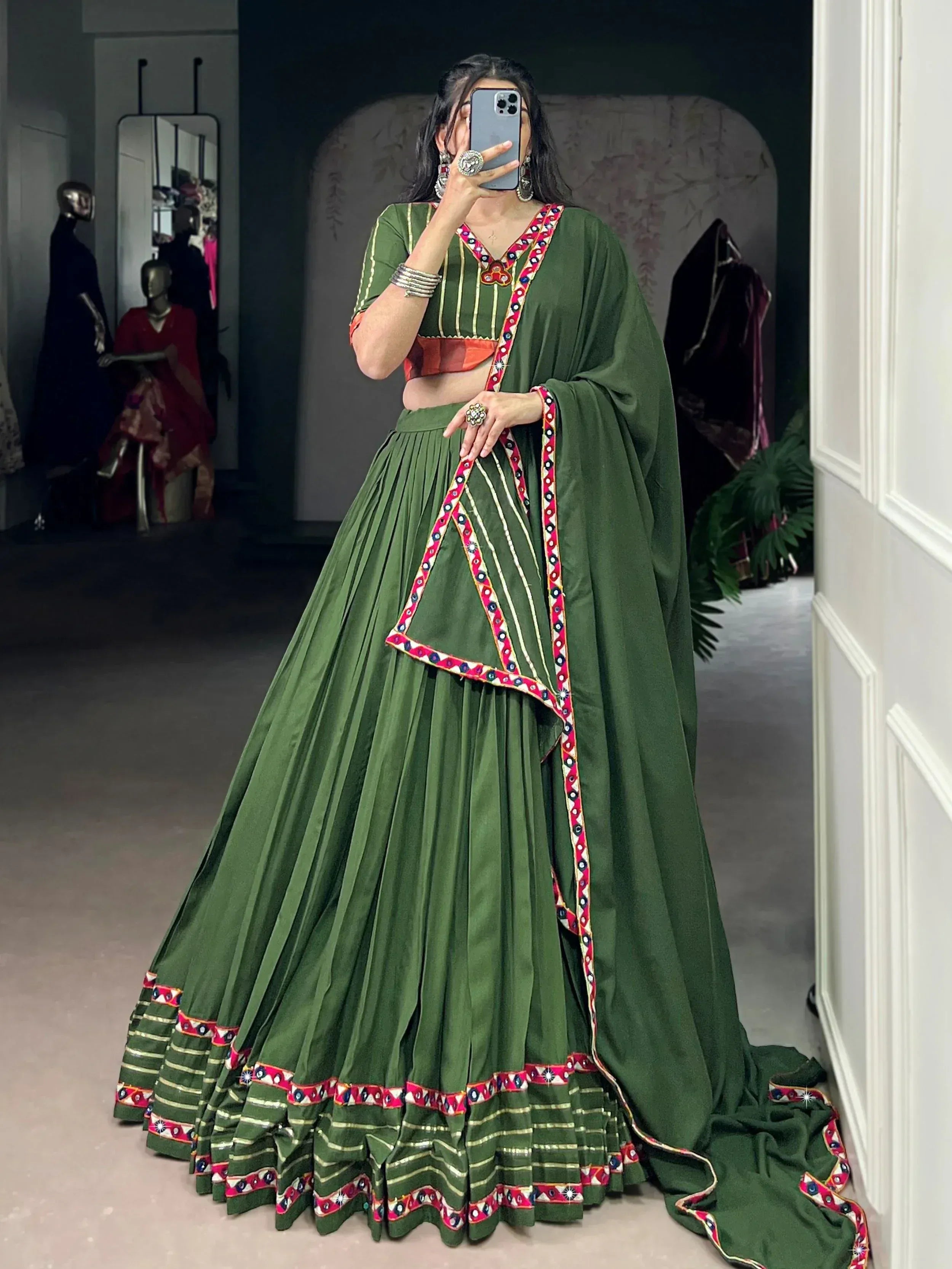 Green ethnic lehenga choli with mirror work and colorful embroidery, perfect for Indian weddings or festive occasions.