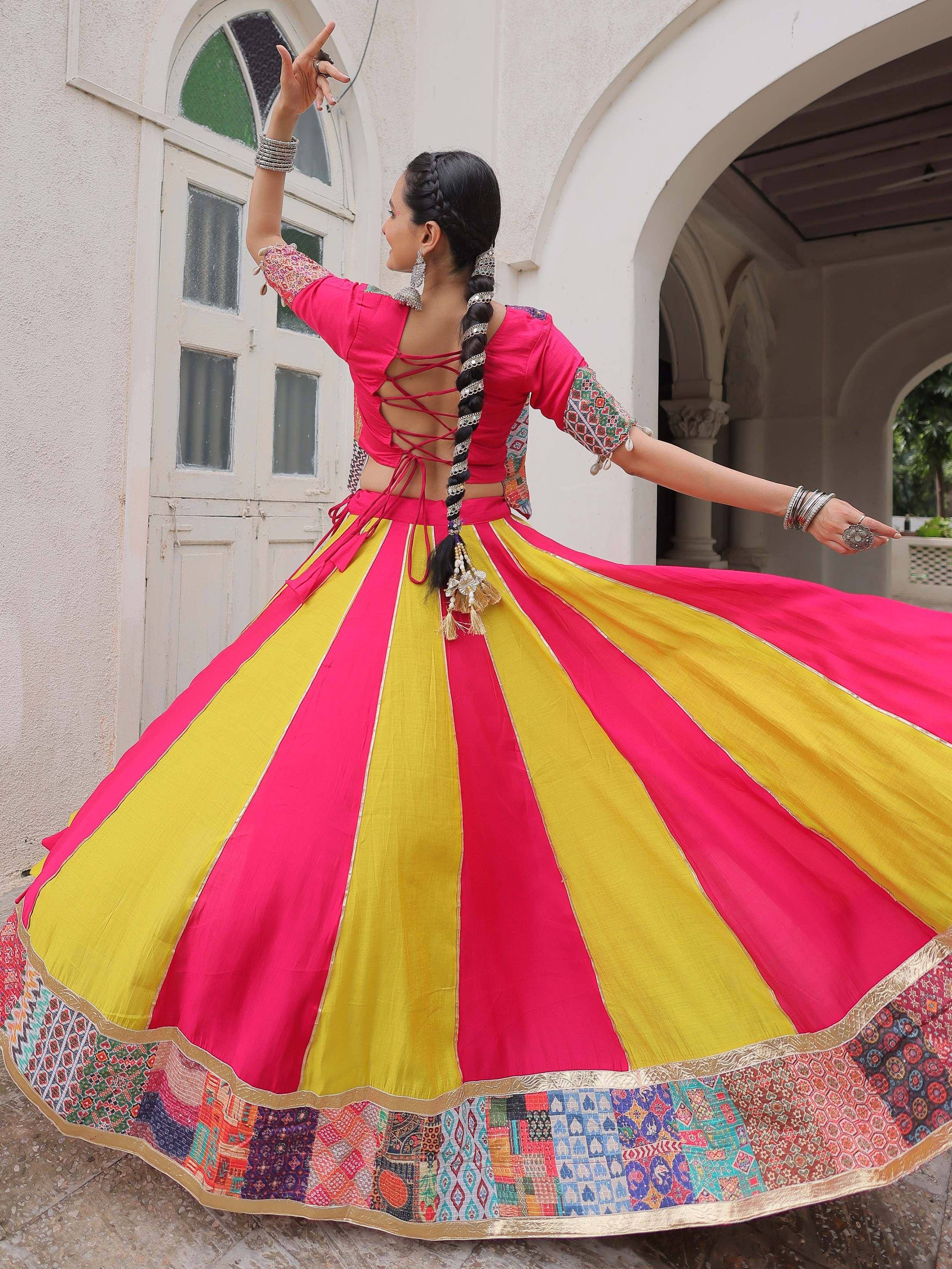 Woman twirling in vibrant pink and yellow Indian ethnic lehenga choli with mirror work, perfect for festive occasions.