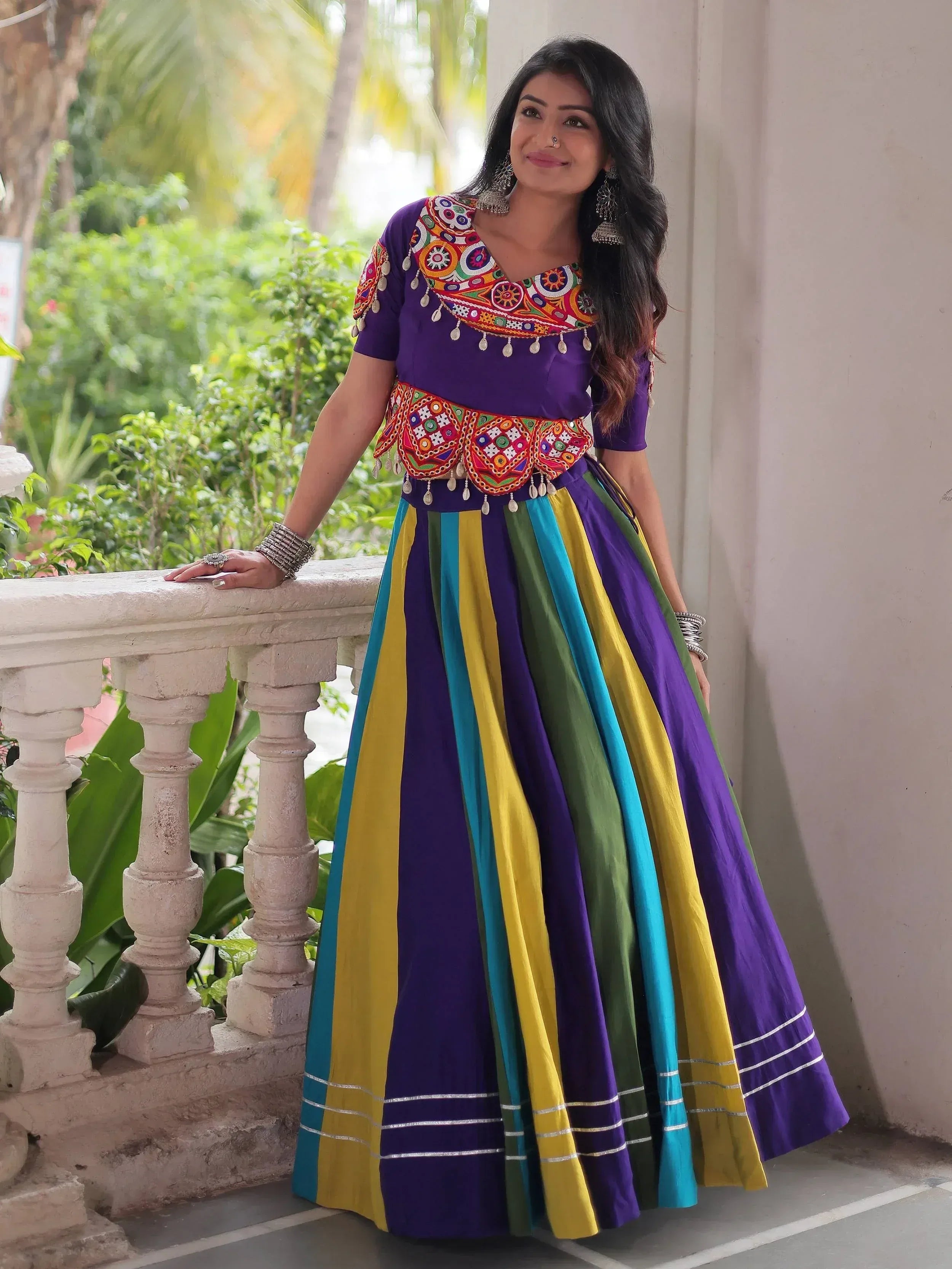 Vibrant purple ethnic gown with colorful striped skirt and intricate embroidery, perfect for festive occasions.