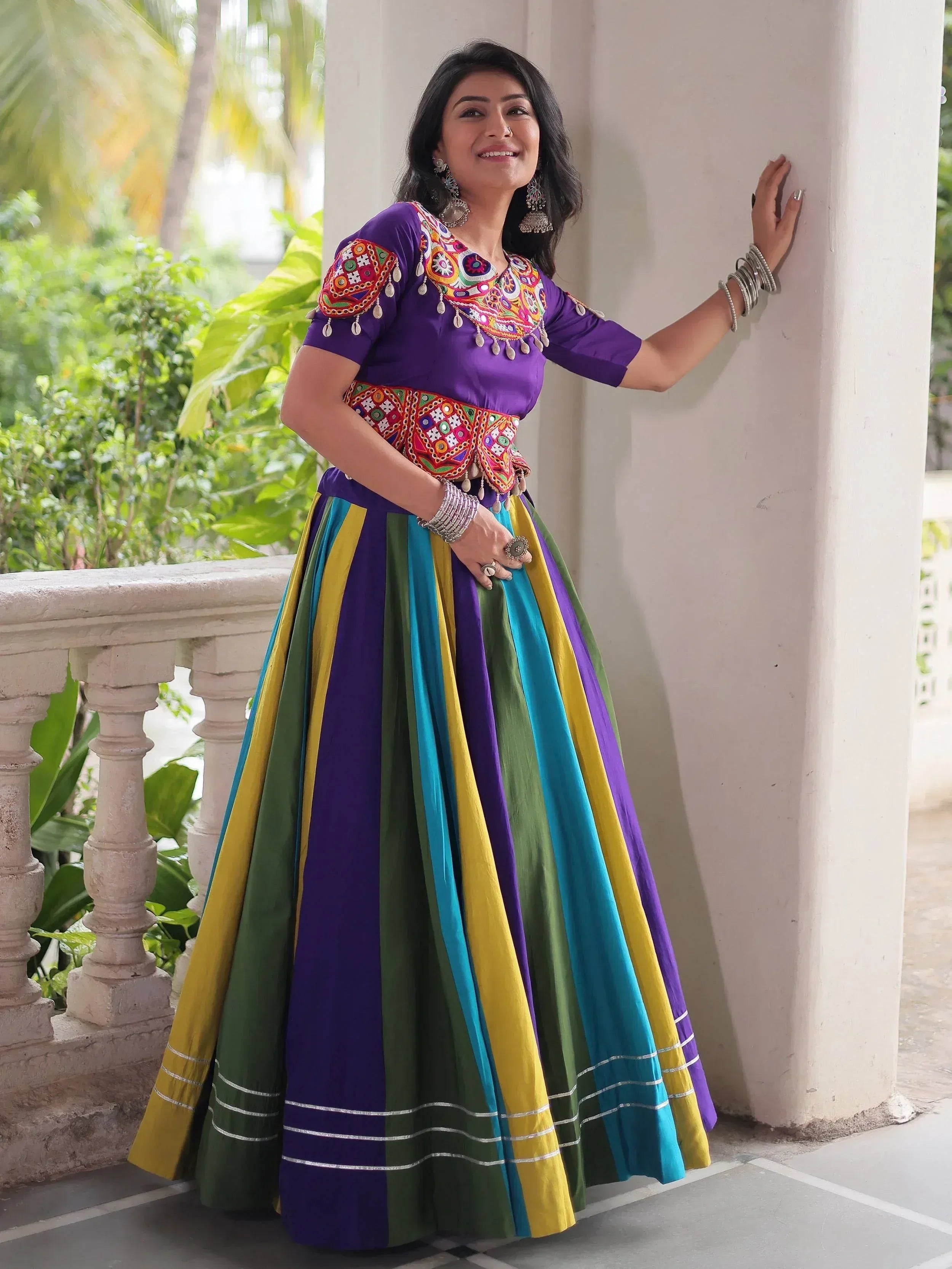 Vibrant purple ethnic gown with colorful striped skirt and embroidered blouse, perfect for festive occasions.