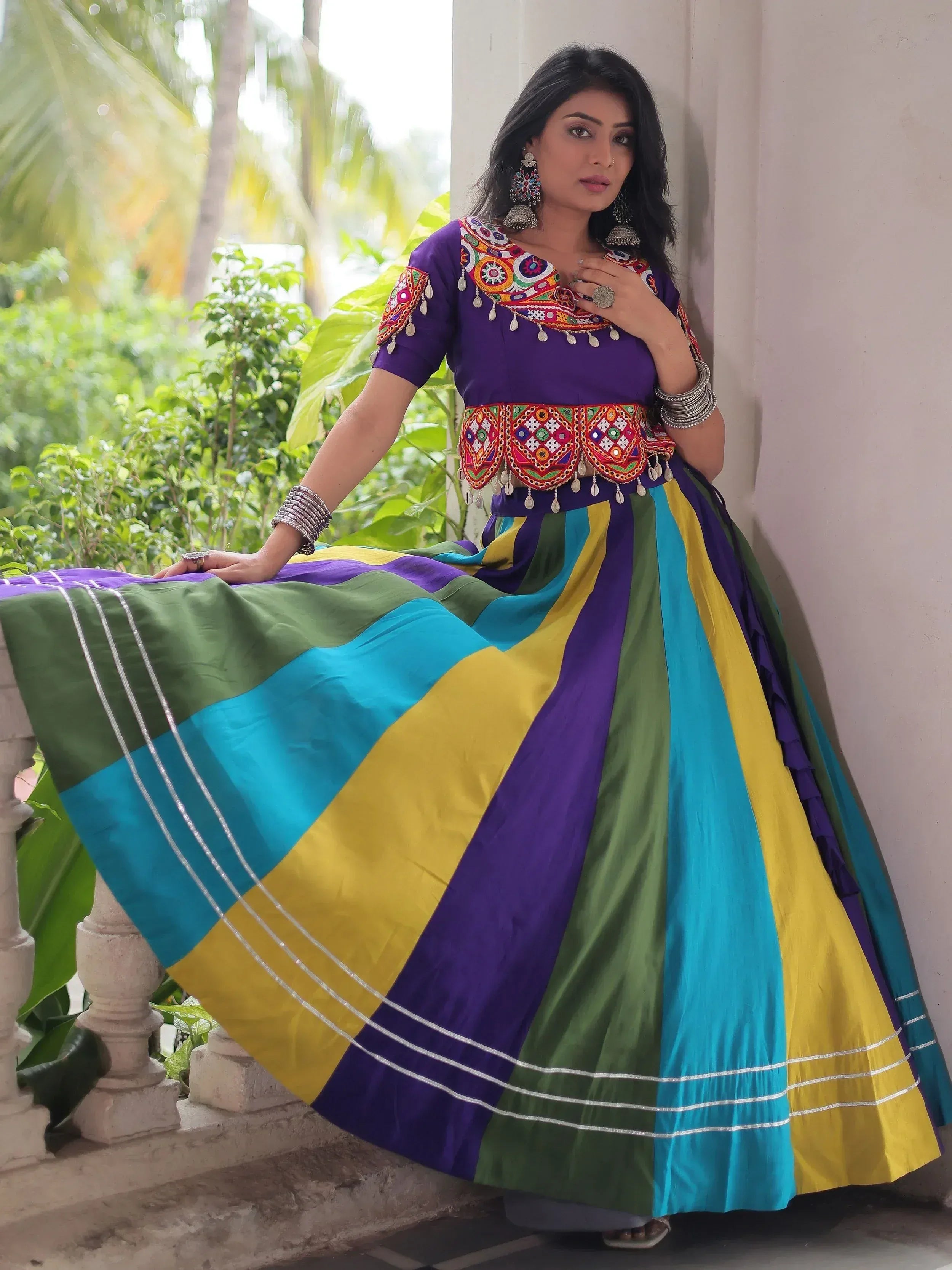 Vibrant Indian ethnic wear with colorful striped skirt and embroidered purple top, perfect for festive occasions.