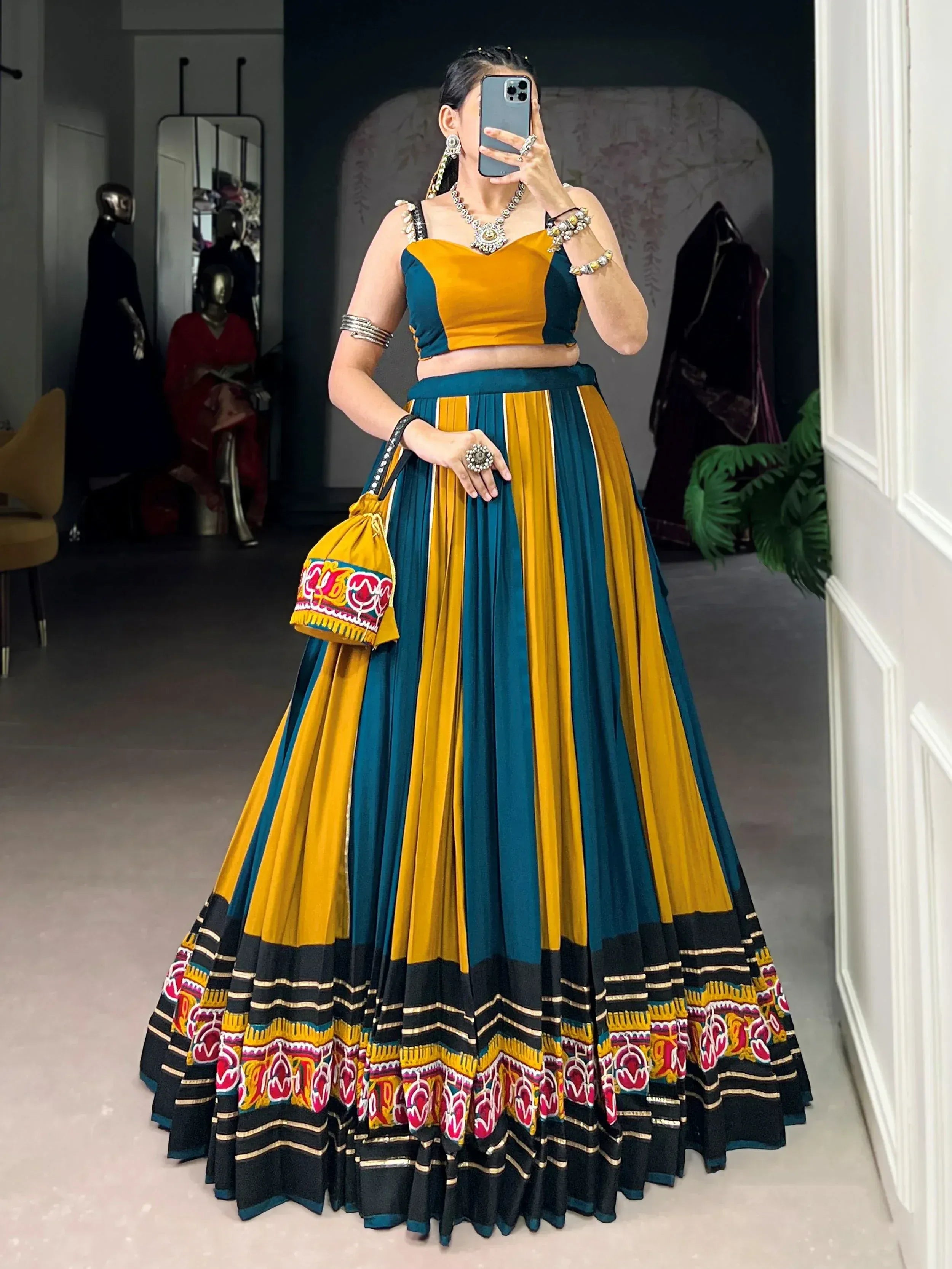 Woman in vibrant yellow and teal ethnic lehenga choli with embroidered skirt, perfect for Indian celebrations