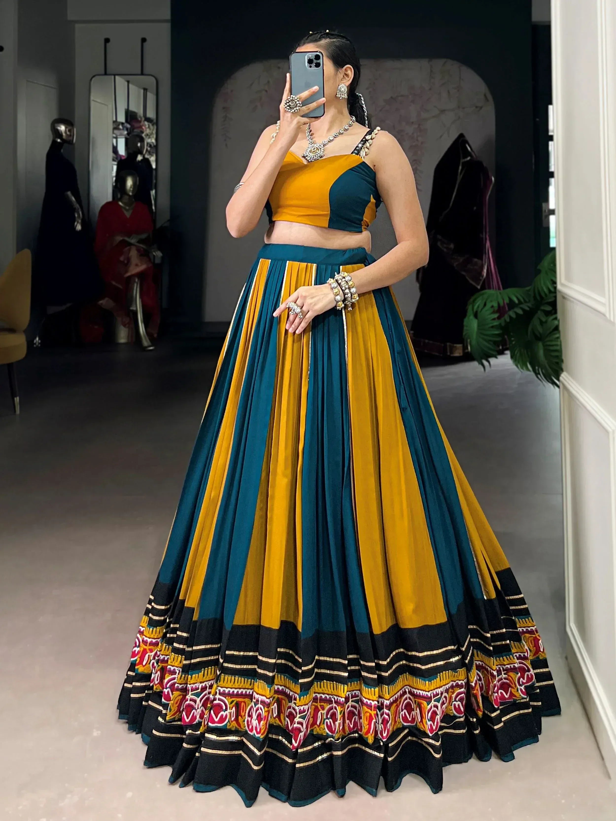 Woman in mustard and teal designer lehenga choli with embroidered border, perfect for Indian ethnic wear occasions