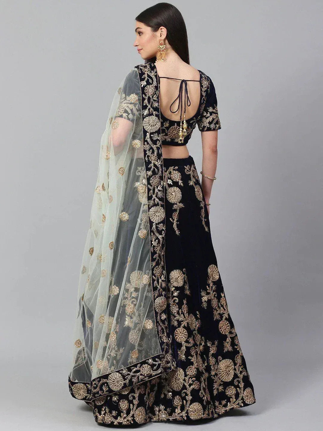 Black velvet lehenga choli with gold floral embroidery and sheer dupatta, back view