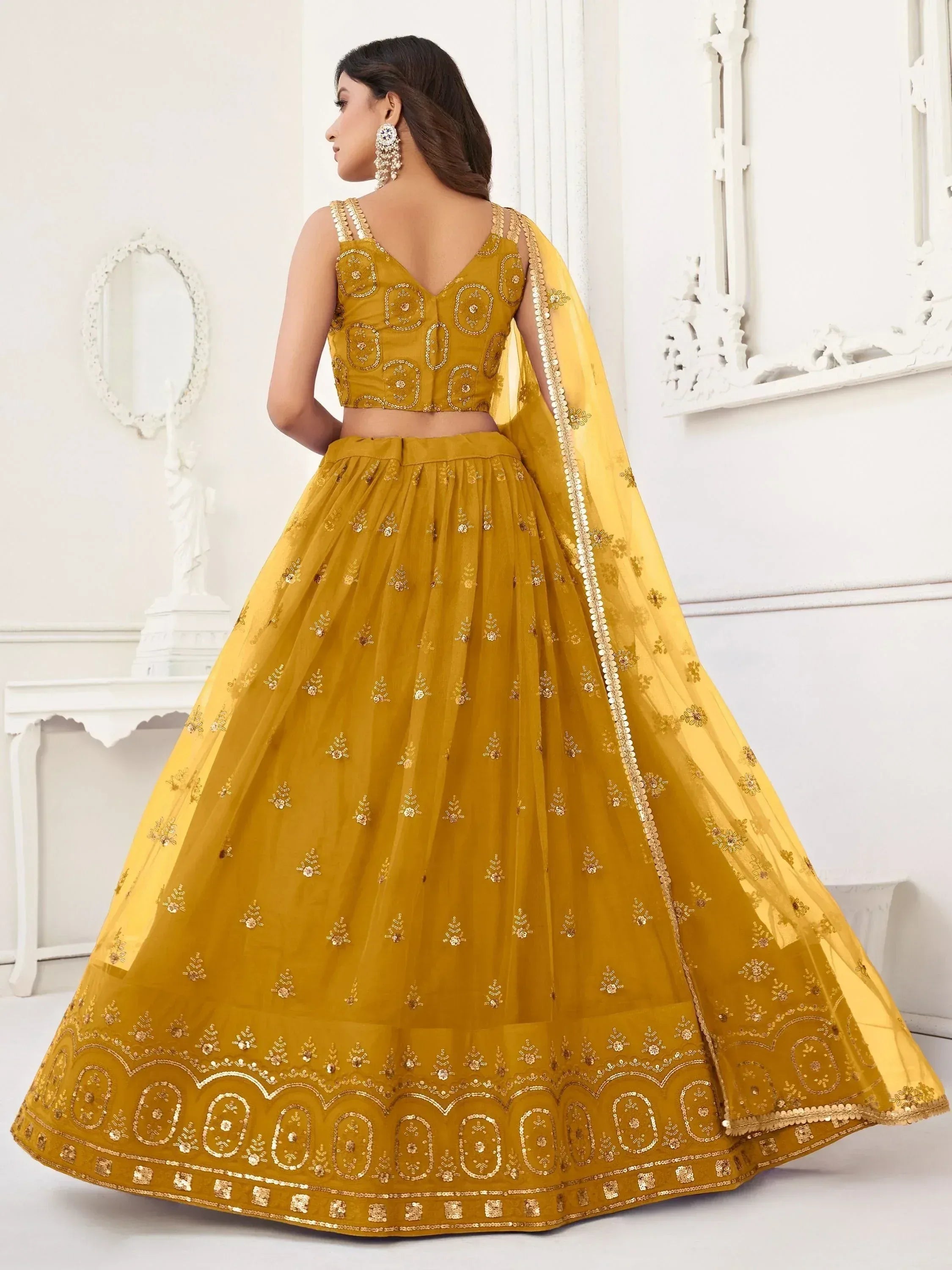 Mustard yellow designer lehenga choli with intricate gold embroidery and sheer dupatta, perfect for Indian weddings and festive occasions.