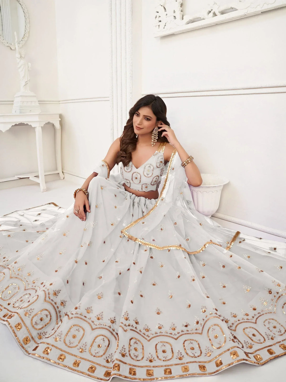 Elegant white lehenga choli with gold embroidery, perfect for Indian weddings and festive occasions.