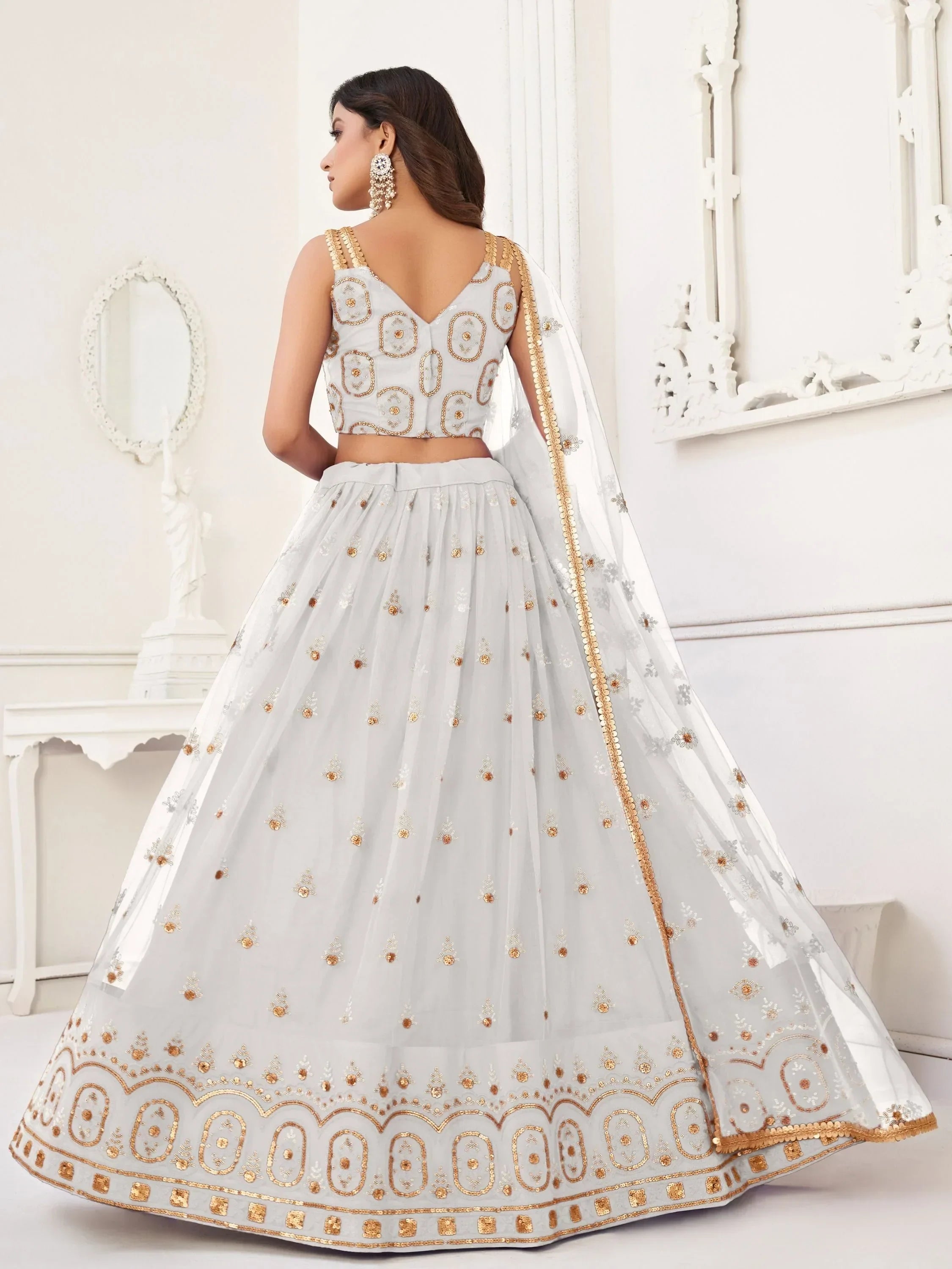 Elegant white lehenga choli with gold embroidery, perfect for Indian weddings and festive occasions.