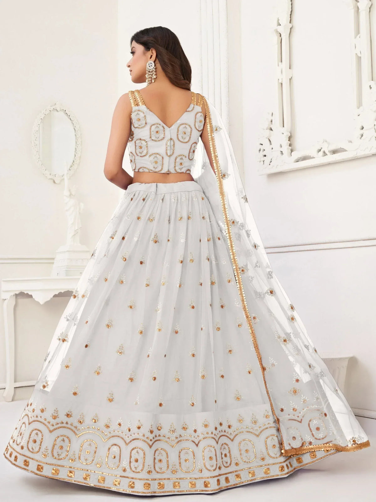Elegant white lehenga choli with gold embroidery, perfect for Indian weddings and festive occasions.