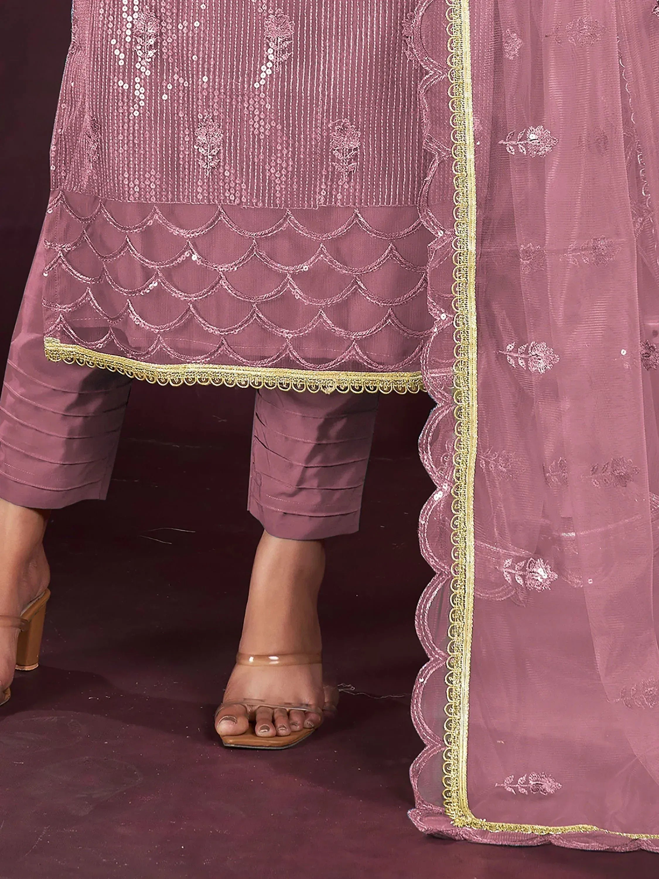 Pink embroidered salwar kameez with scalloped hem and gold trim, paired with sheer dupatta and heels