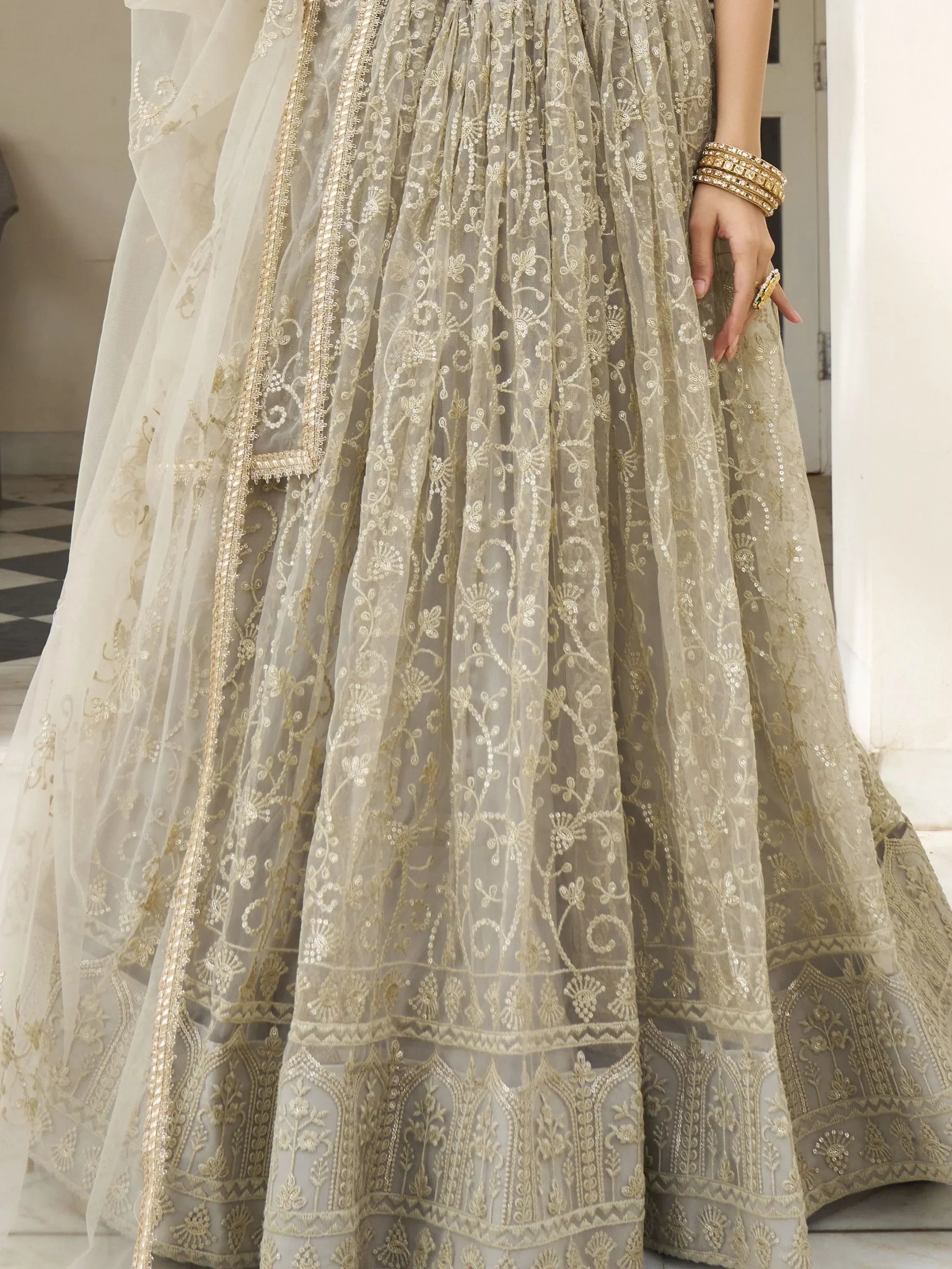 Elegant beige lehenga choli with gold embroidery and sheer dupatta, perfect for Indian weddings and festive occasions.