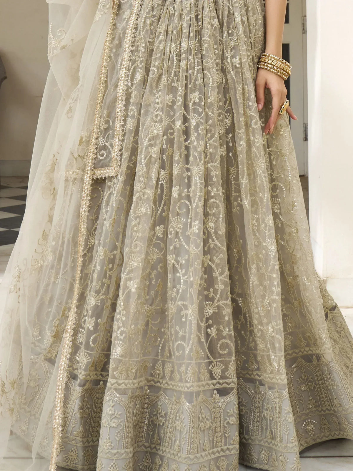 Elegant beige lehenga choli with gold embroidery and sheer dupatta, perfect for Indian weddings and festive occasions.