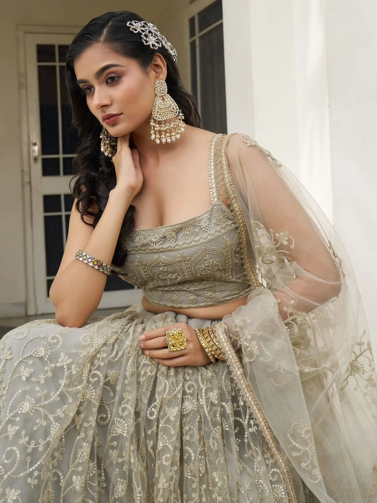 Elegant grey lehenga choli with gold embroidery, sheer dupatta, and traditional Indian jewelry for weddings