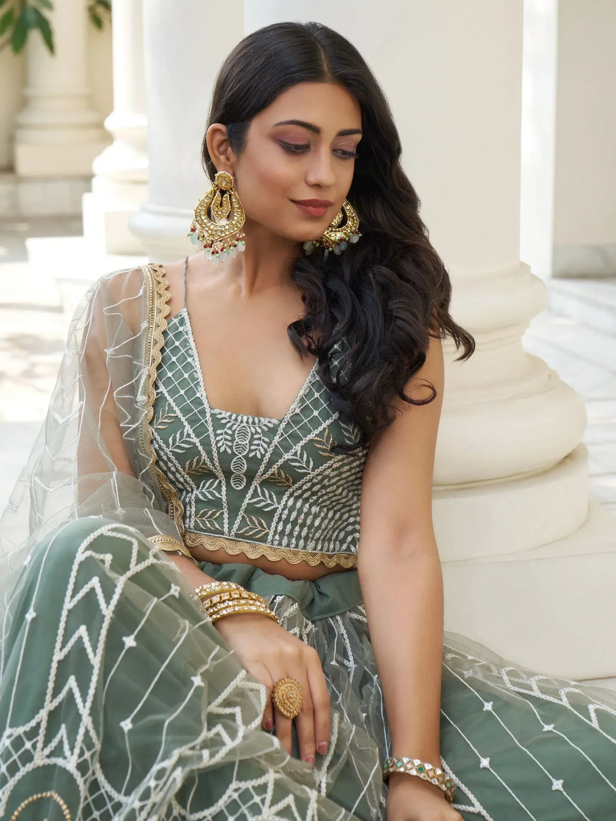 Elegant green embroidered lehenga choli with gold jewelry, perfect for Indian ethnic wear occasions.