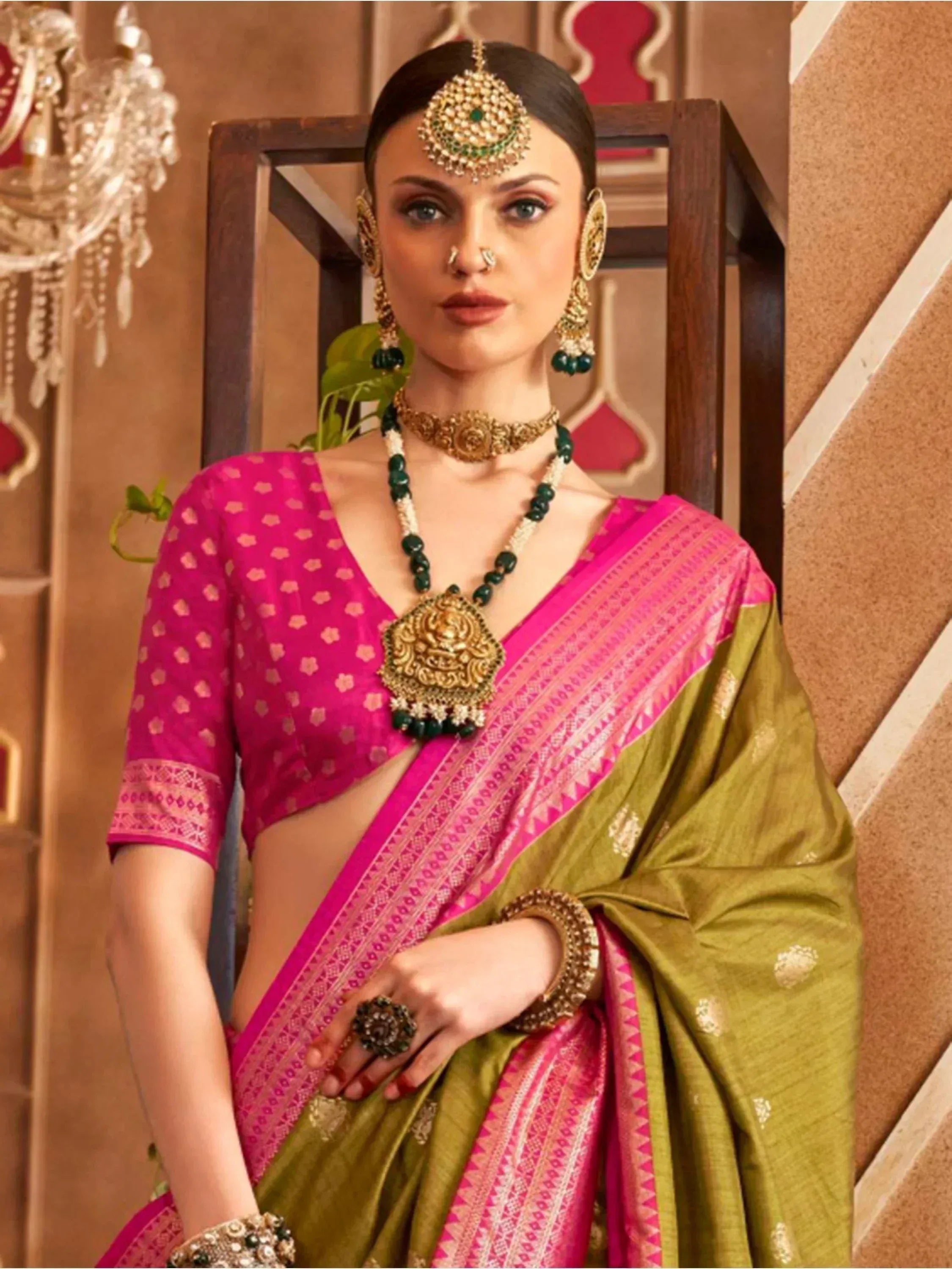 Woman in vibrant pink and olive green saree with gold jewelry, traditional Indian ethnic wear
