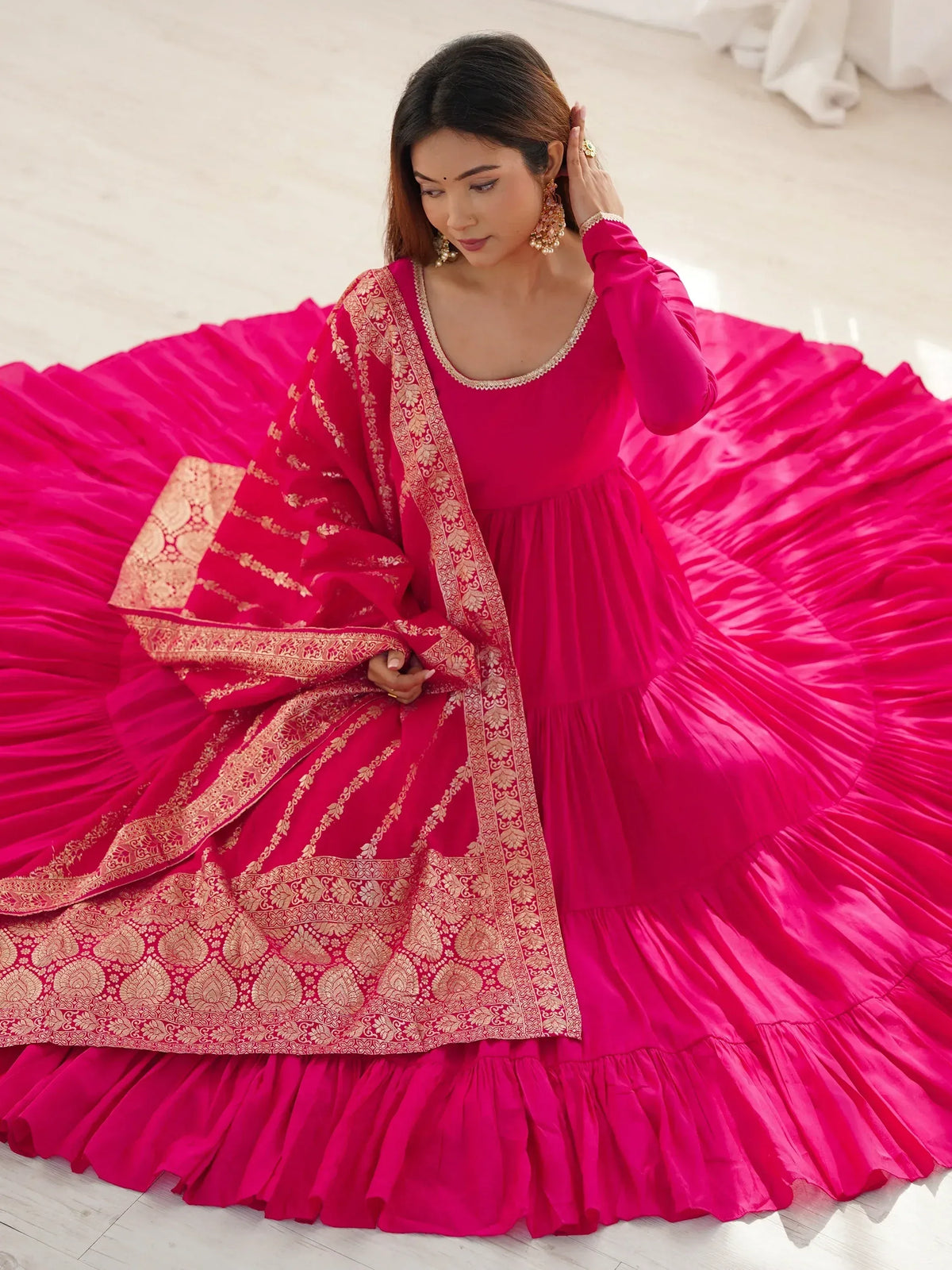Fuchsia pink ethnic gown with gold embroidery and ruffled skirt, perfect for Indian weddings and festivals