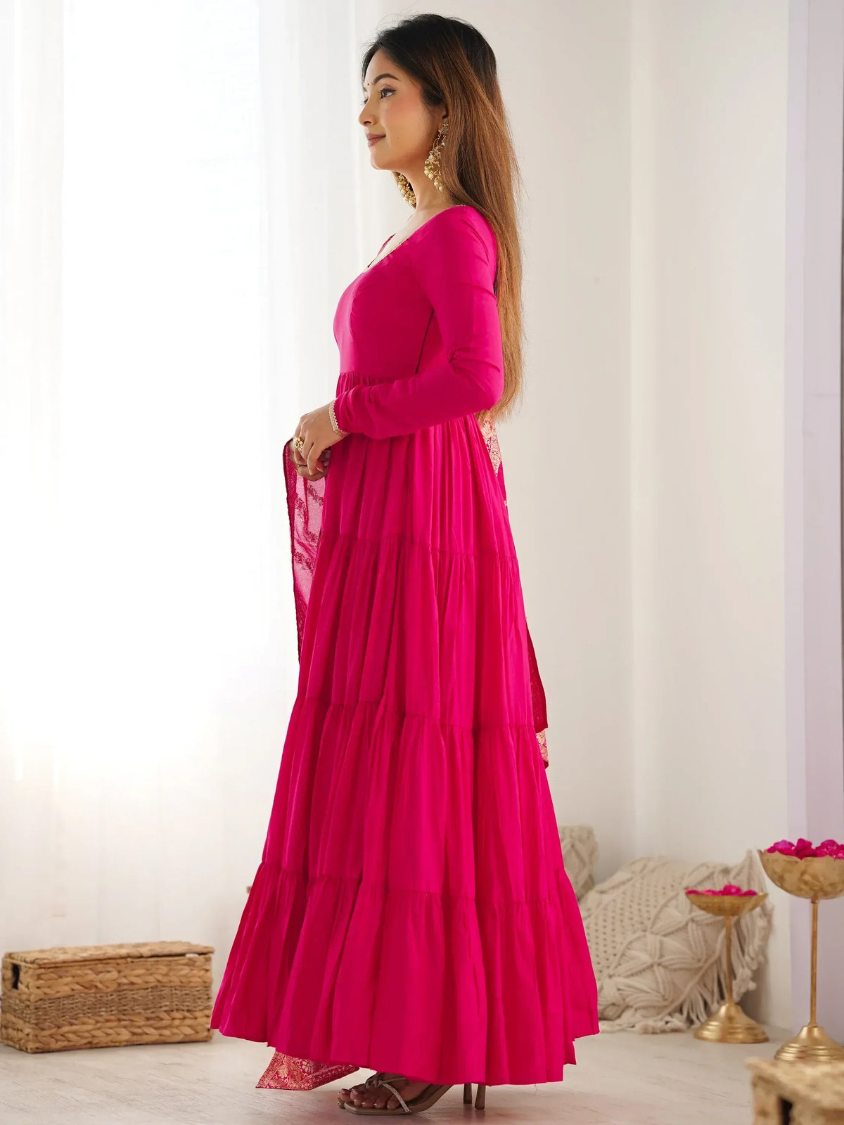 Woman in vibrant pink tiered ethnic gown with lace dupatta, perfect for Indian occasions