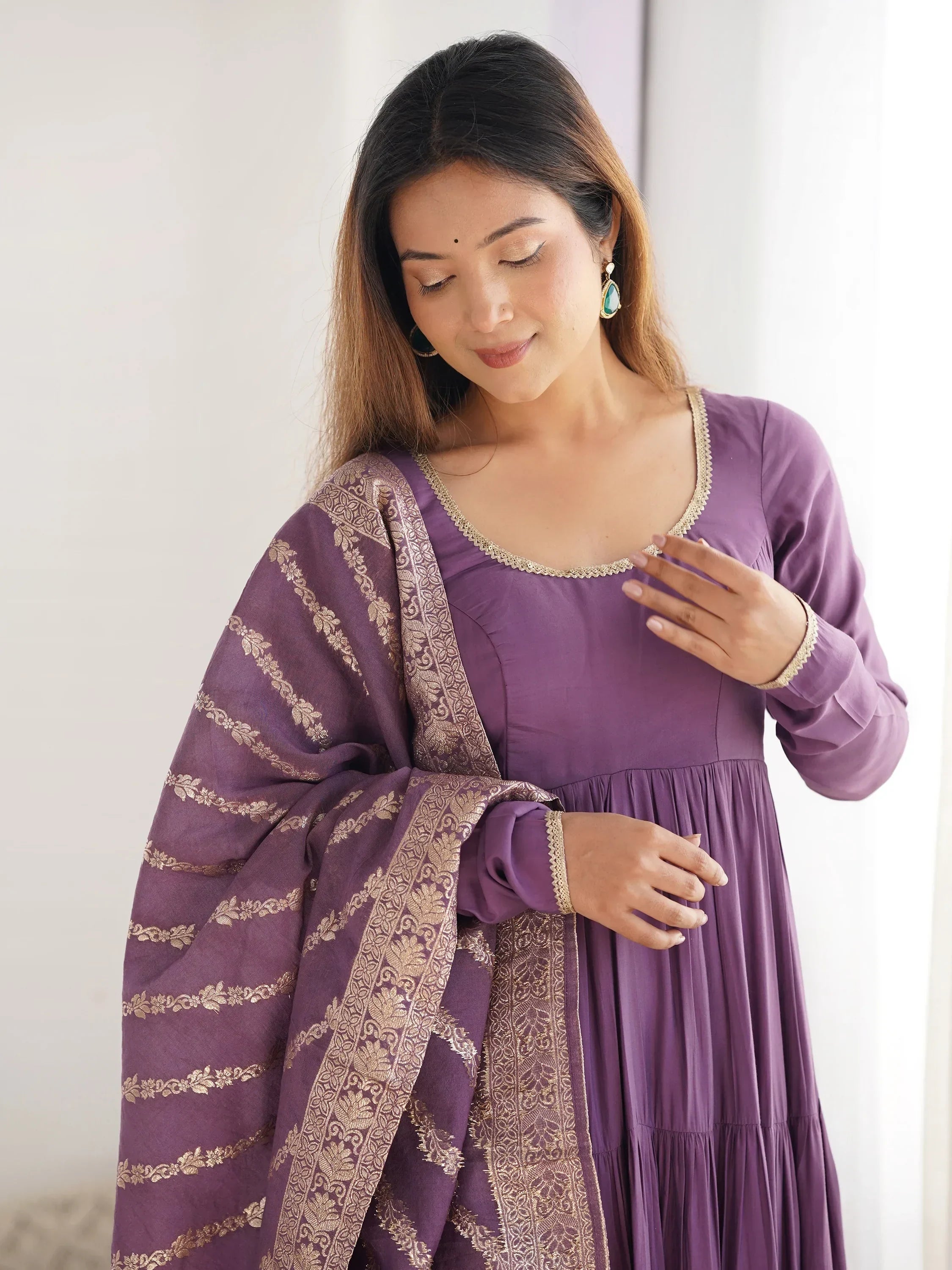 Woman in purple ethnic gown with gold embroidered dupatta, traditional Indian attire