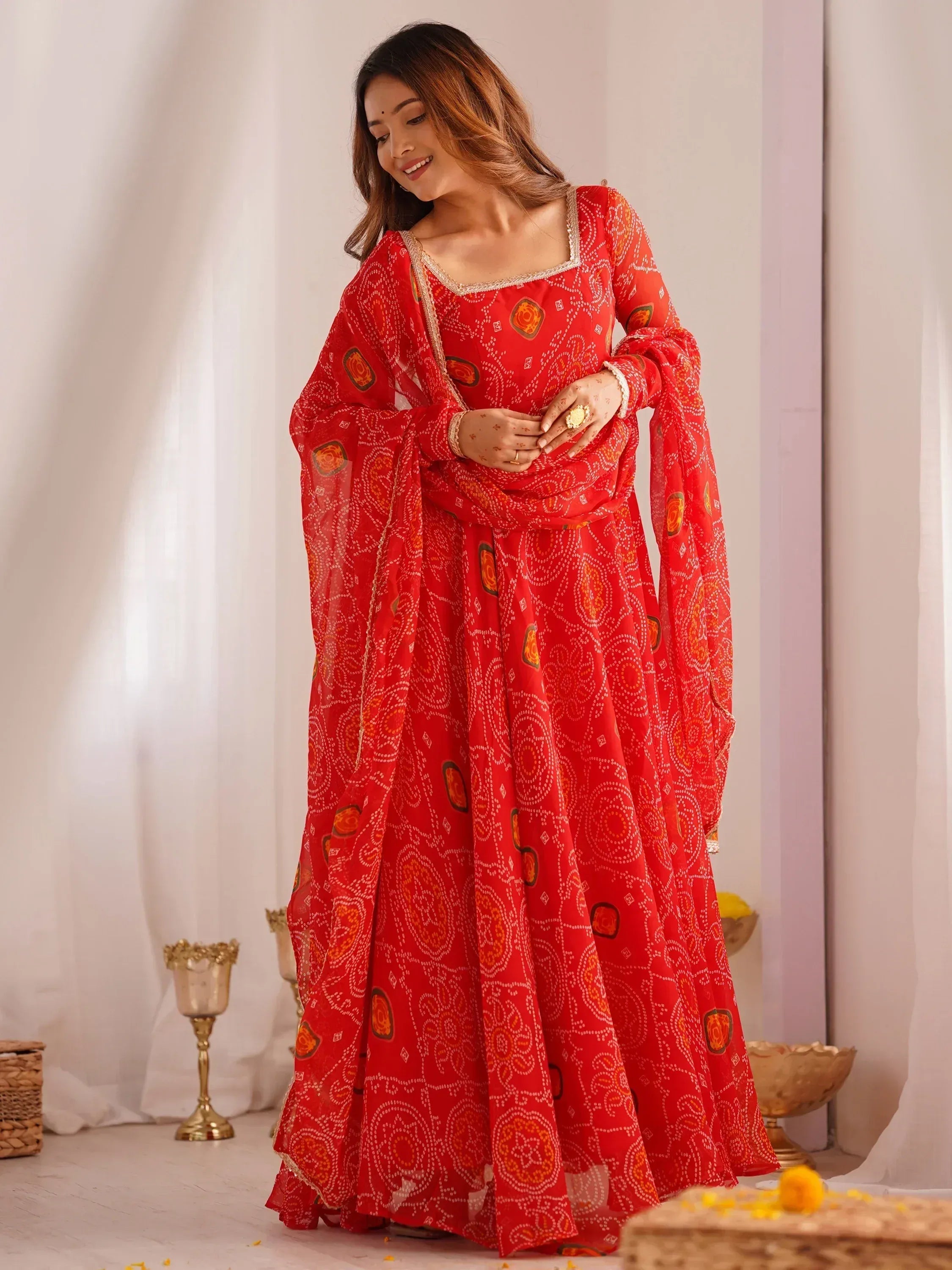 Red printed ethnic gown with flared sleeves and gold trim, perfect for Indian festive occasions