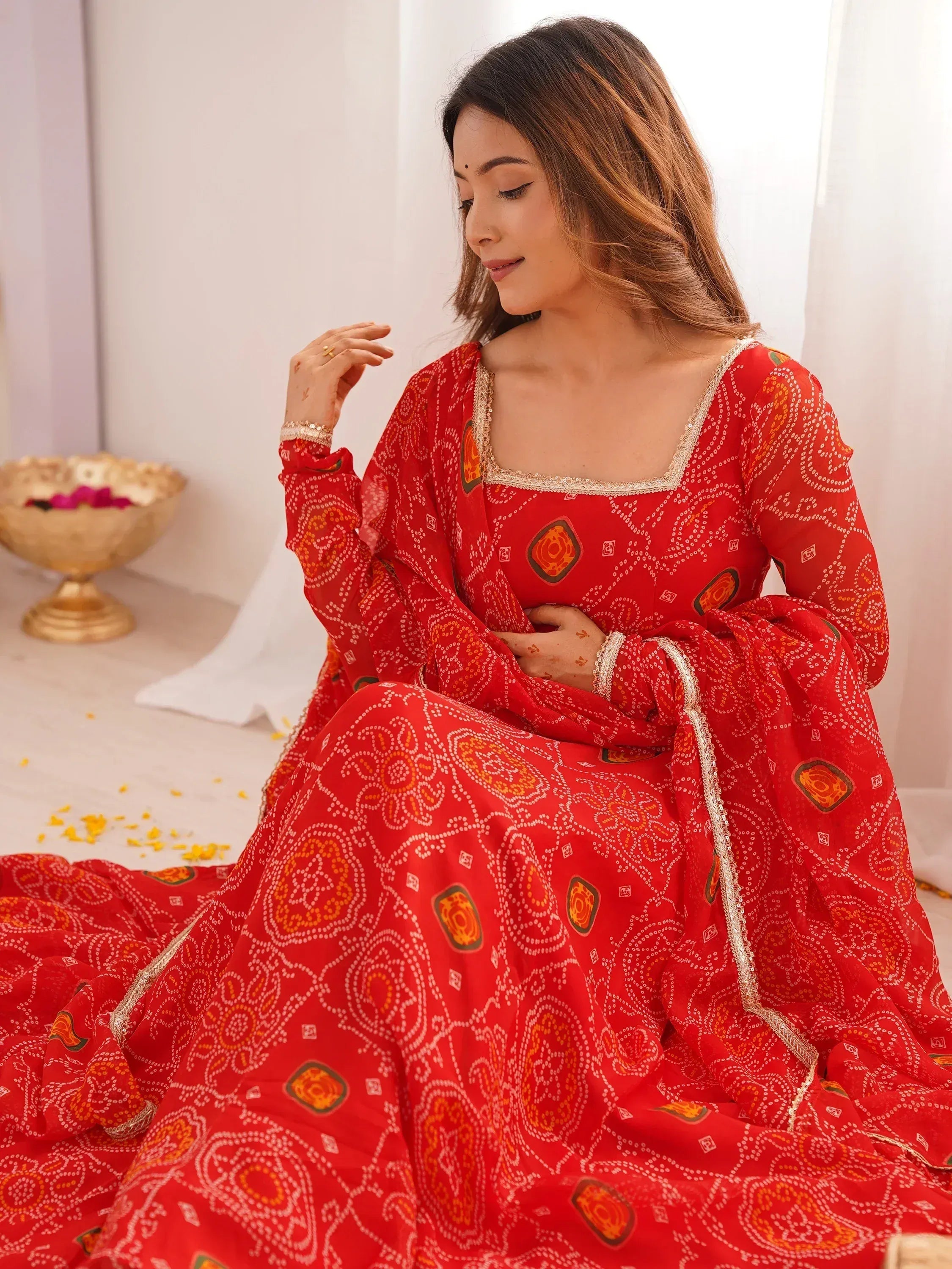 Red printed ethnic gown with gold trim, perfect for Indian celebrations and festive occasions.