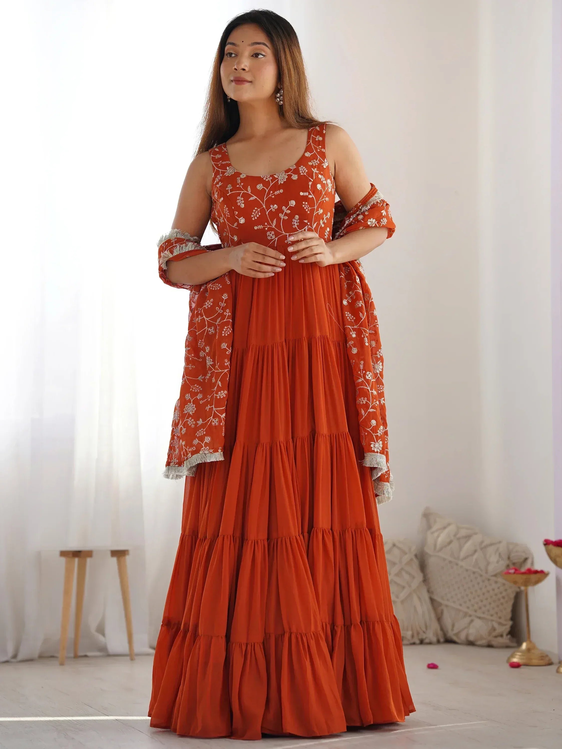 Orange embroidered tiered ethnic gown with off-shoulder sleeves, perfect for Indian festive occasions