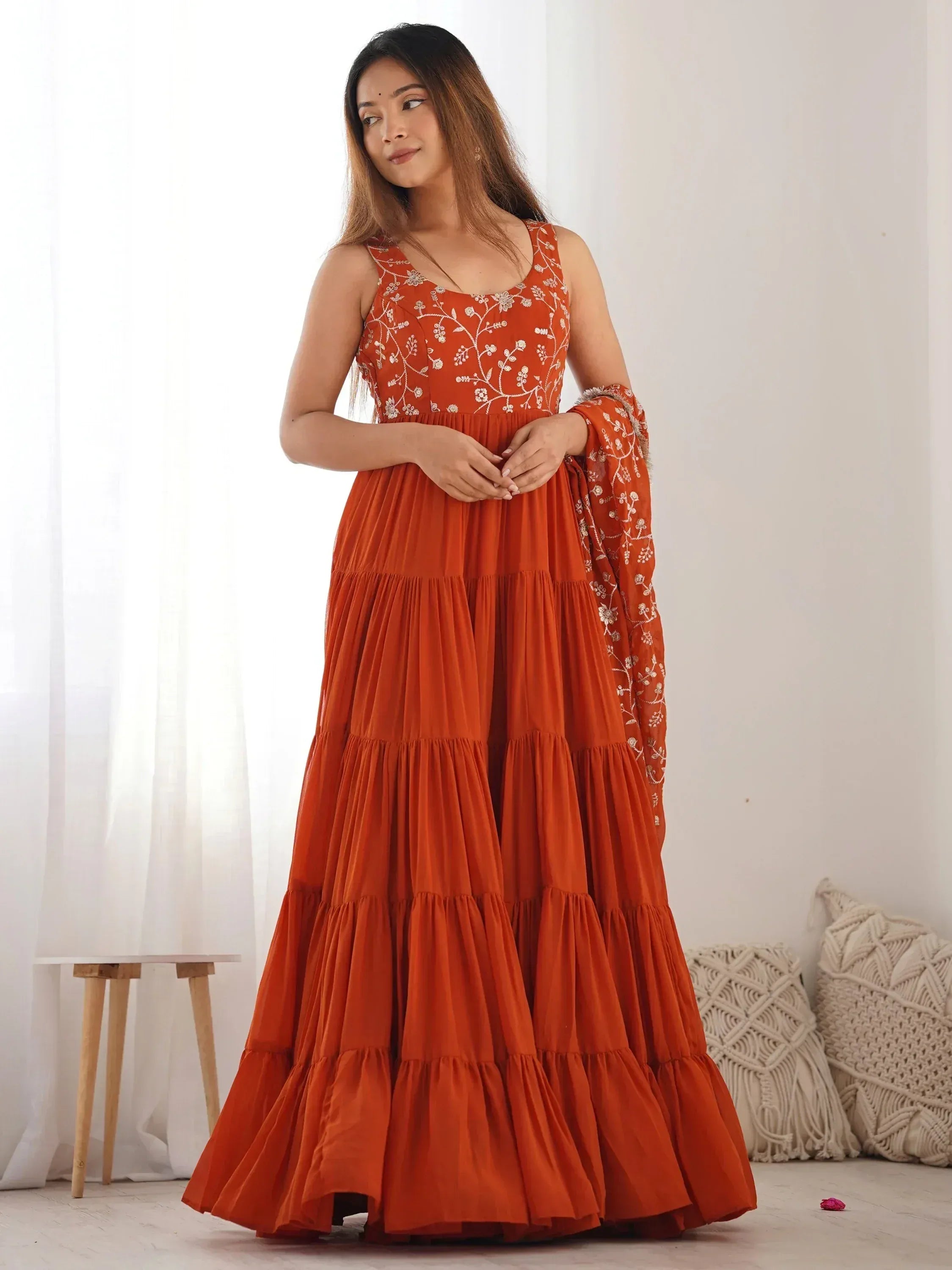 Orange tiered ethnic gown with floral embroidery and matching dupatta, perfect for Indian occasions.