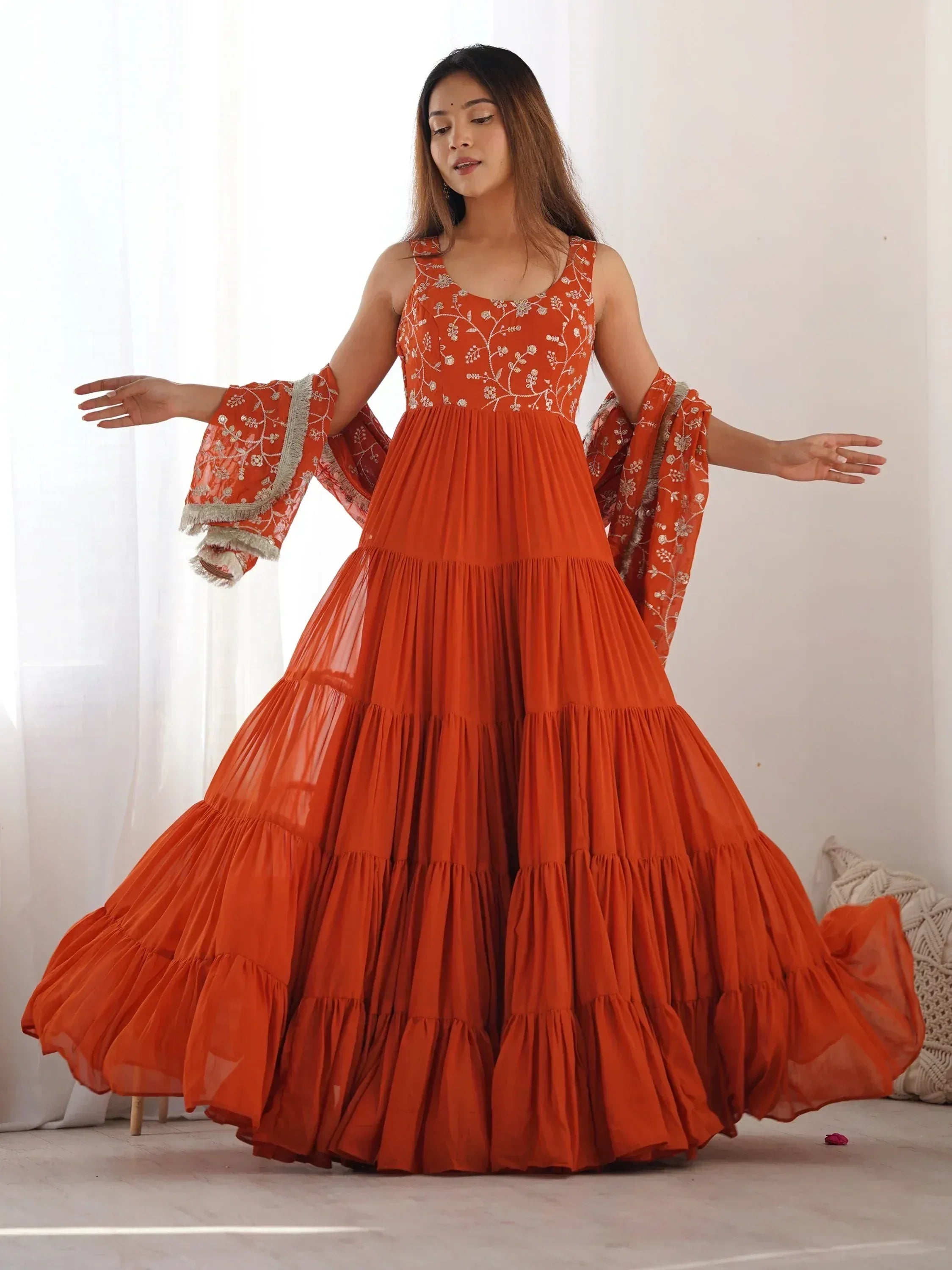Orange embroidered tiered ethnic gown with flared sleeves, perfect for Indian festive occasions