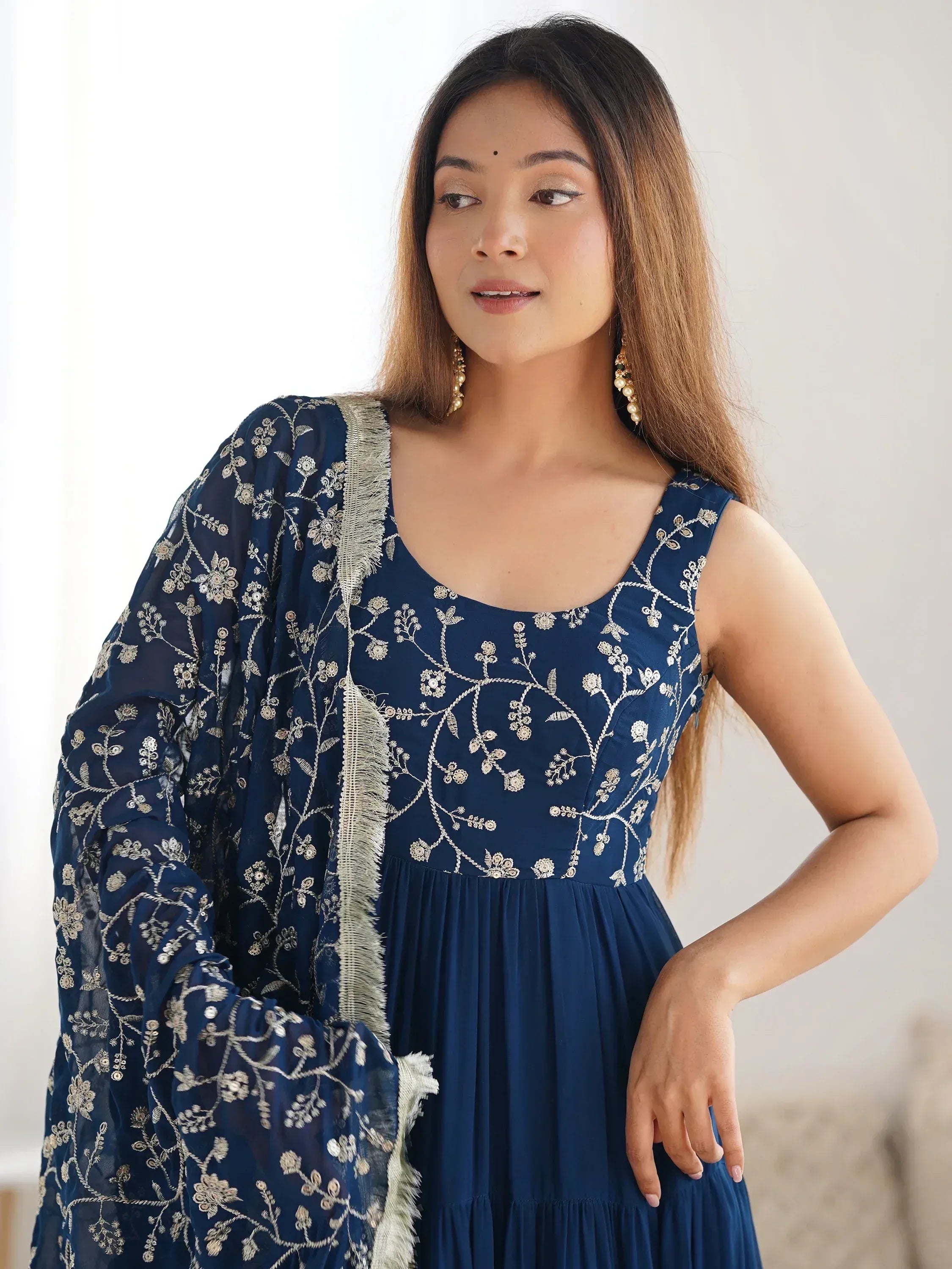 Woman wearing a navy blue ethnic gown with silver floral embroidery and matching dupatta