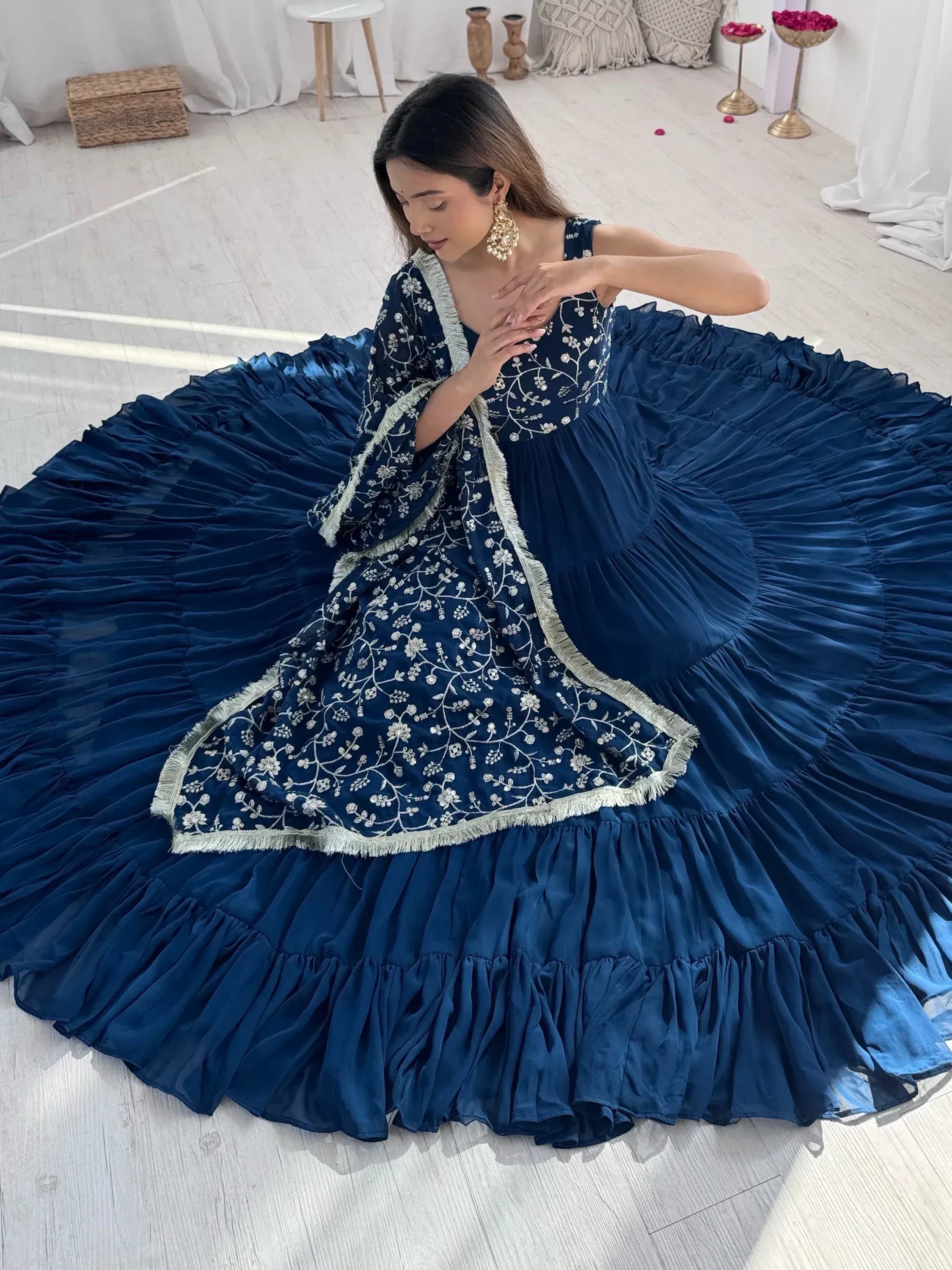 Woman in navy blue embroidered lehenga choli with dupatta sitting on floor