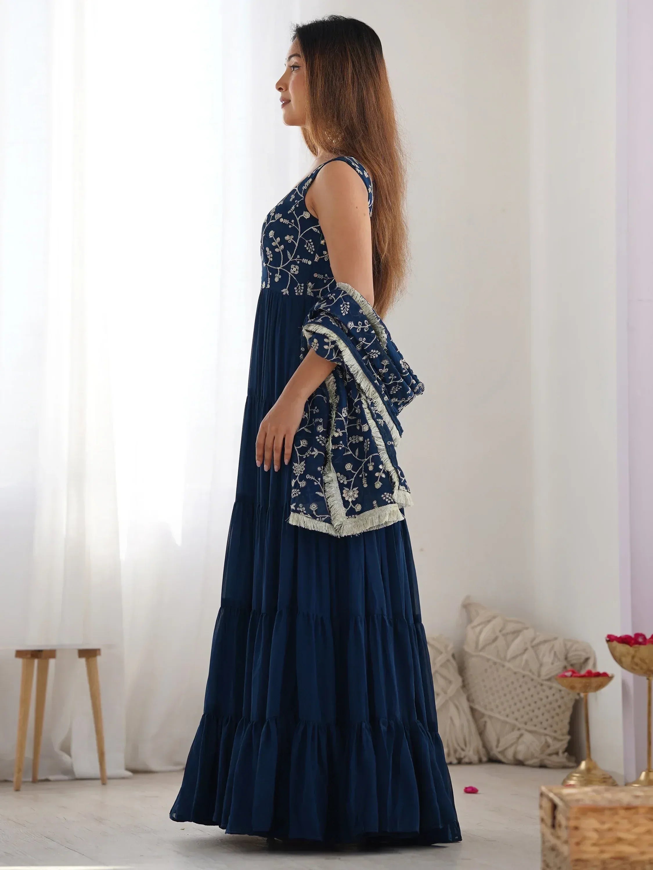 Woman in navy blue embroidered ethnic gown with dupatta, side view, indoors