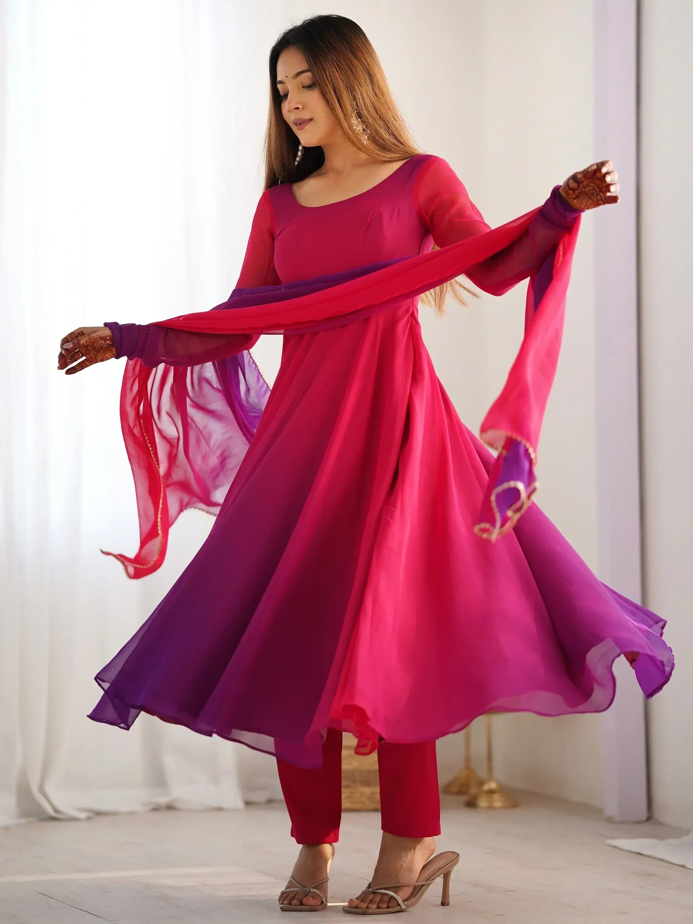 Woman in vibrant pink and purple ethnic anarkali suit with sheer dupatta, perfect for Indian festive occasions