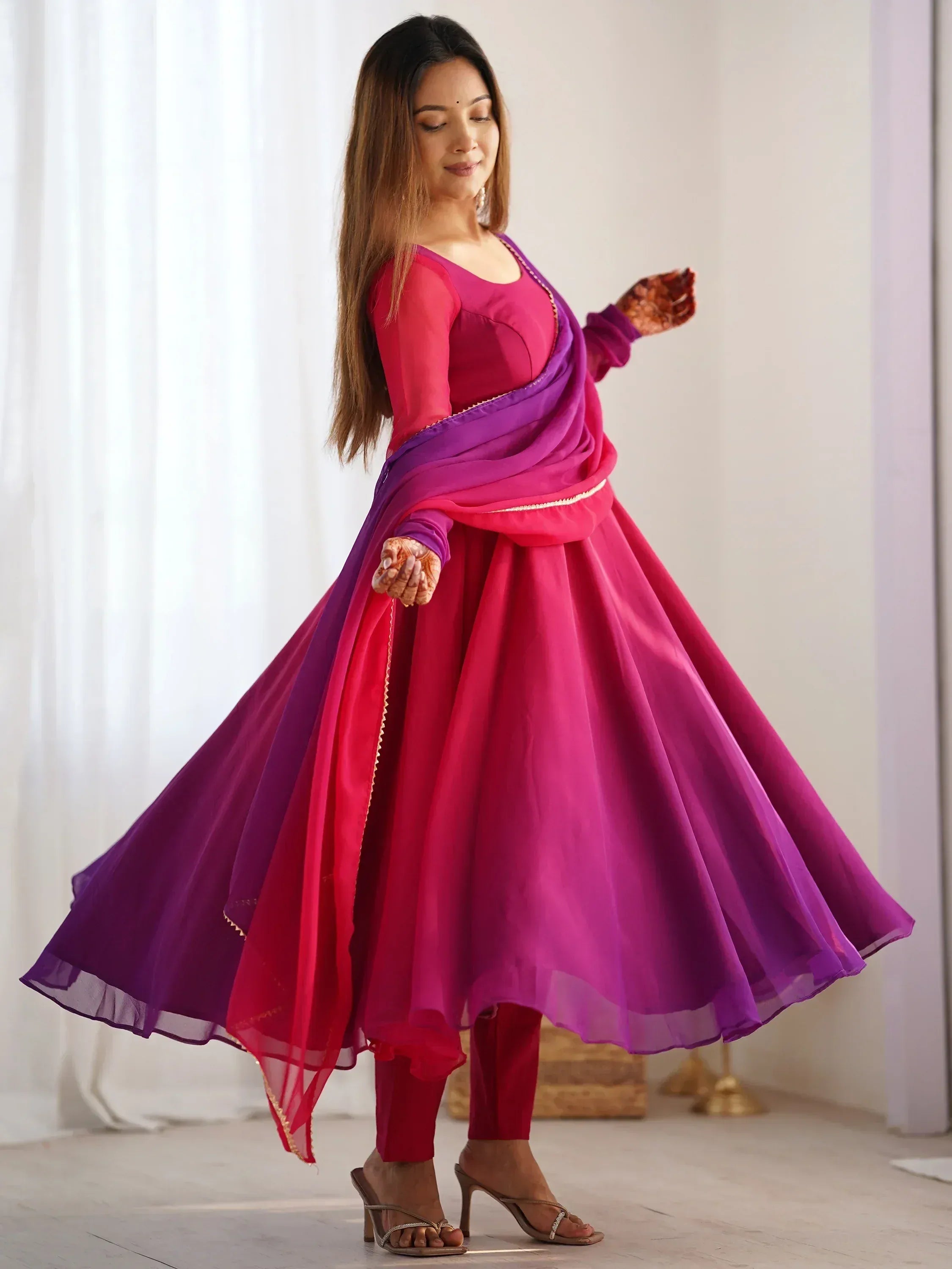 Woman in vibrant pink and purple ethnic gown with flowing dupatta, perfect for Indian celebrations
