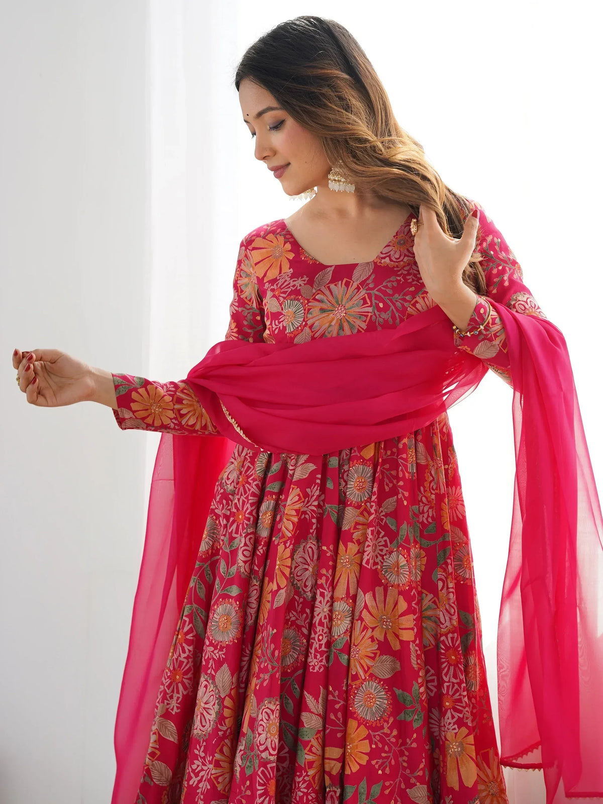 Woman in vibrant pink floral Indian ethnic wear with matching dupatta, perfect for festive occasions.