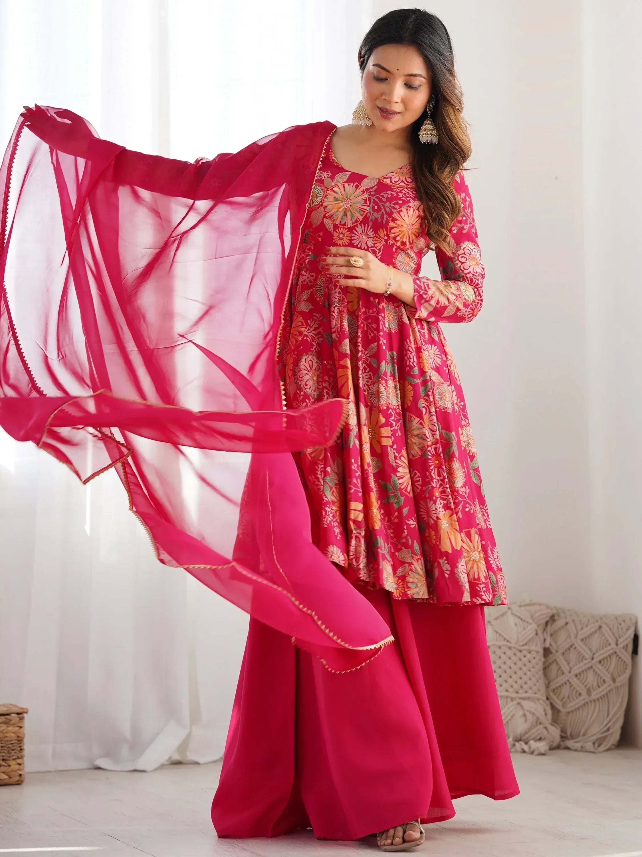 Woman in vibrant pink floral anarkali suit with matching dupatta, ethnic Indian wear
