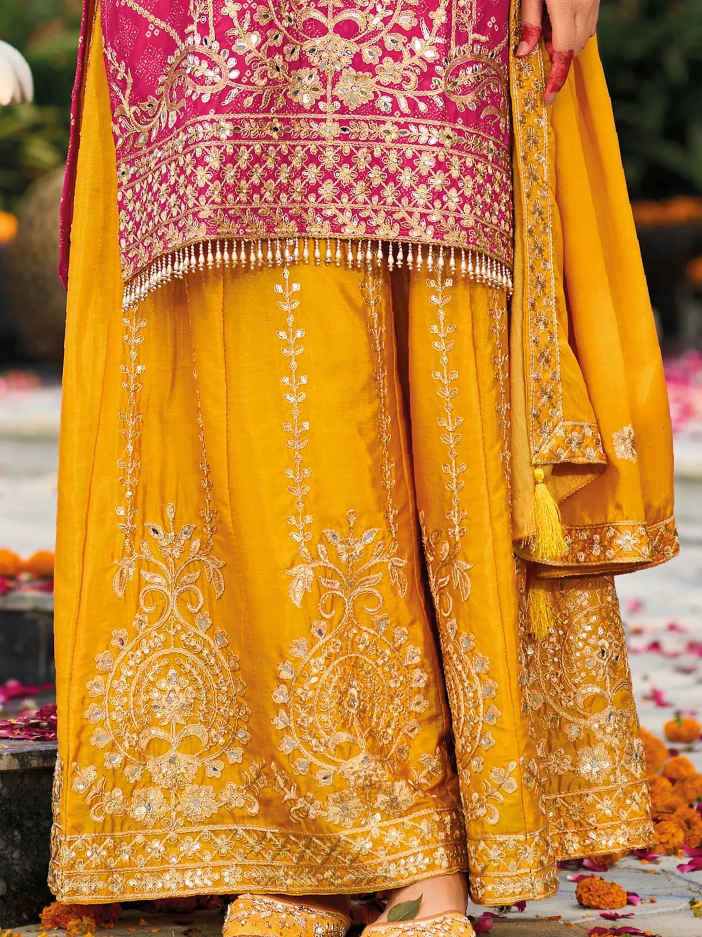 Pink and mustard yellow embroidered lehenga choli with gold threadwork and mirror detailing, perfect for Indian weddings and festive occasions.