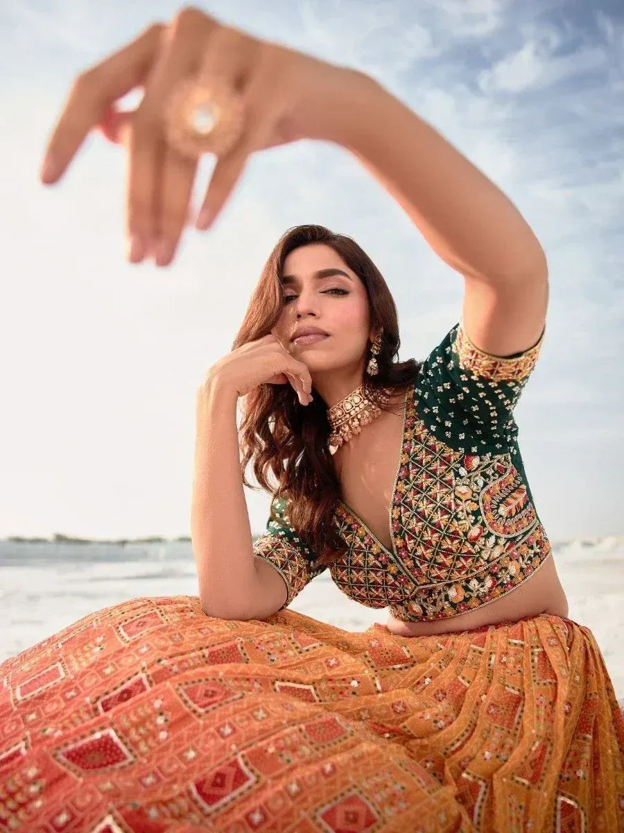 Woman in vibrant Indian lehenga choli with intricate embroidery, posing on beach under sky