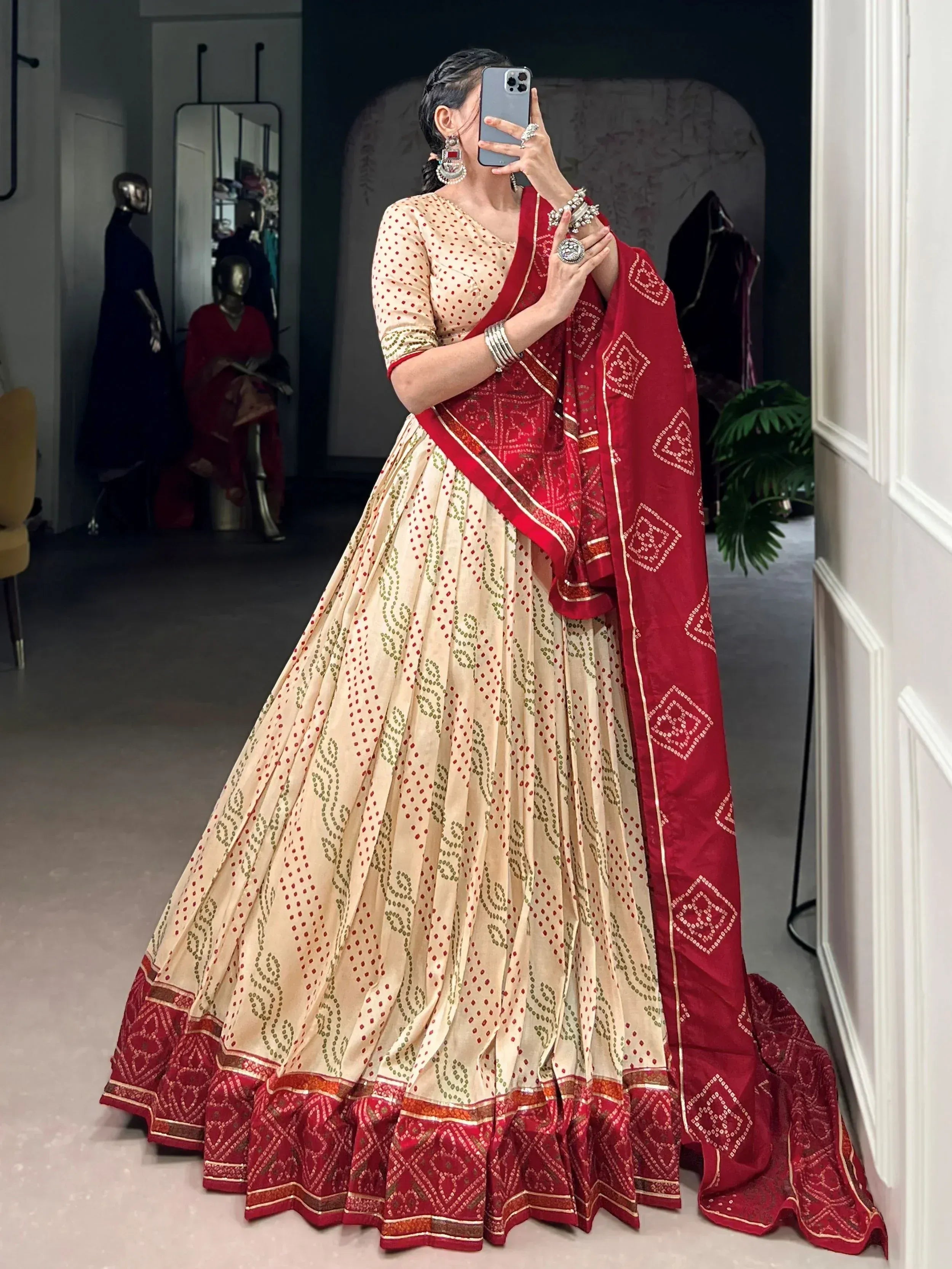 Woman in elegant beige and red lehenga choli with intricate patterns, perfect for Indian ethnic wear occasions.