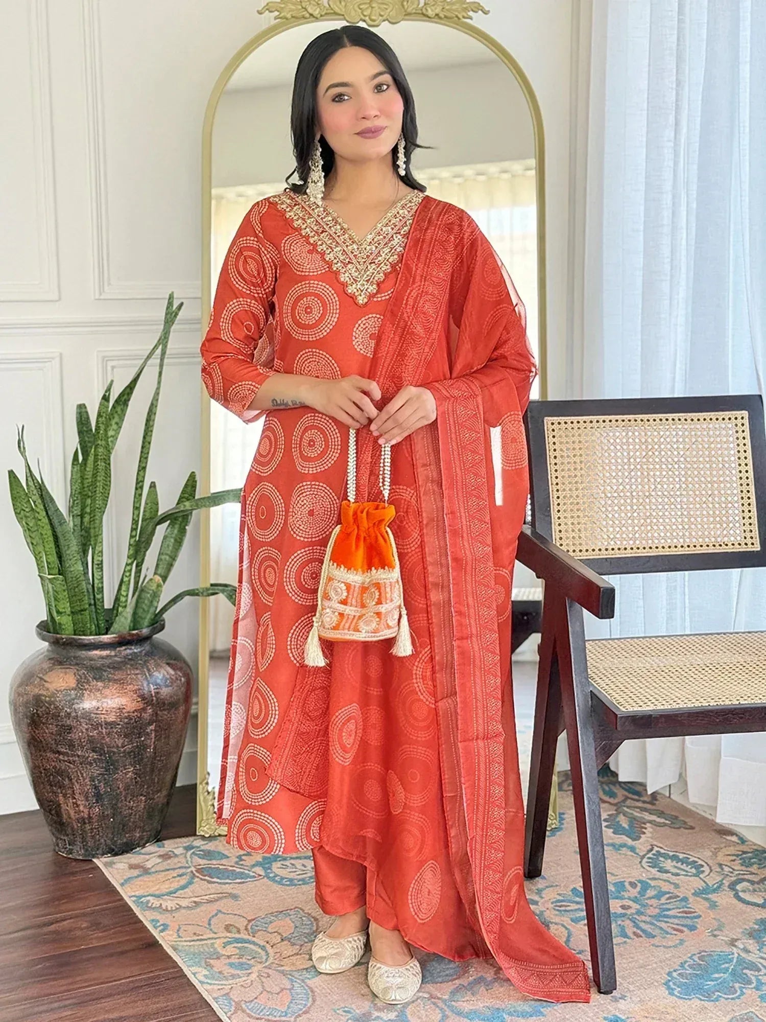 Orange printed salwar kameez with gold embroidery, matching dupatta and potli bag for ethnic wear