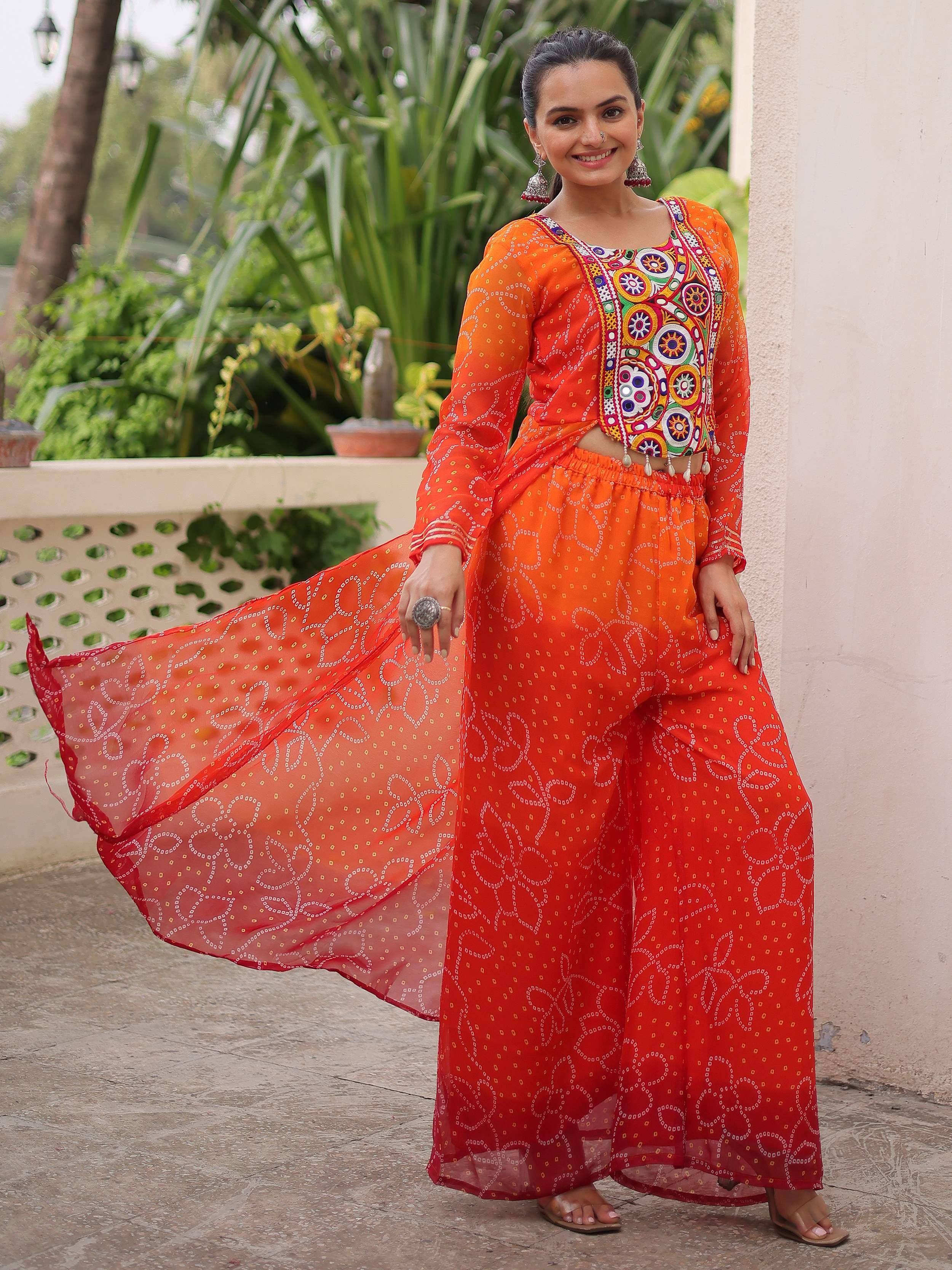Vibrant orange ethnic wear with mirror work, bandhani print palazzo and dupatta, perfect for Indian festivals.