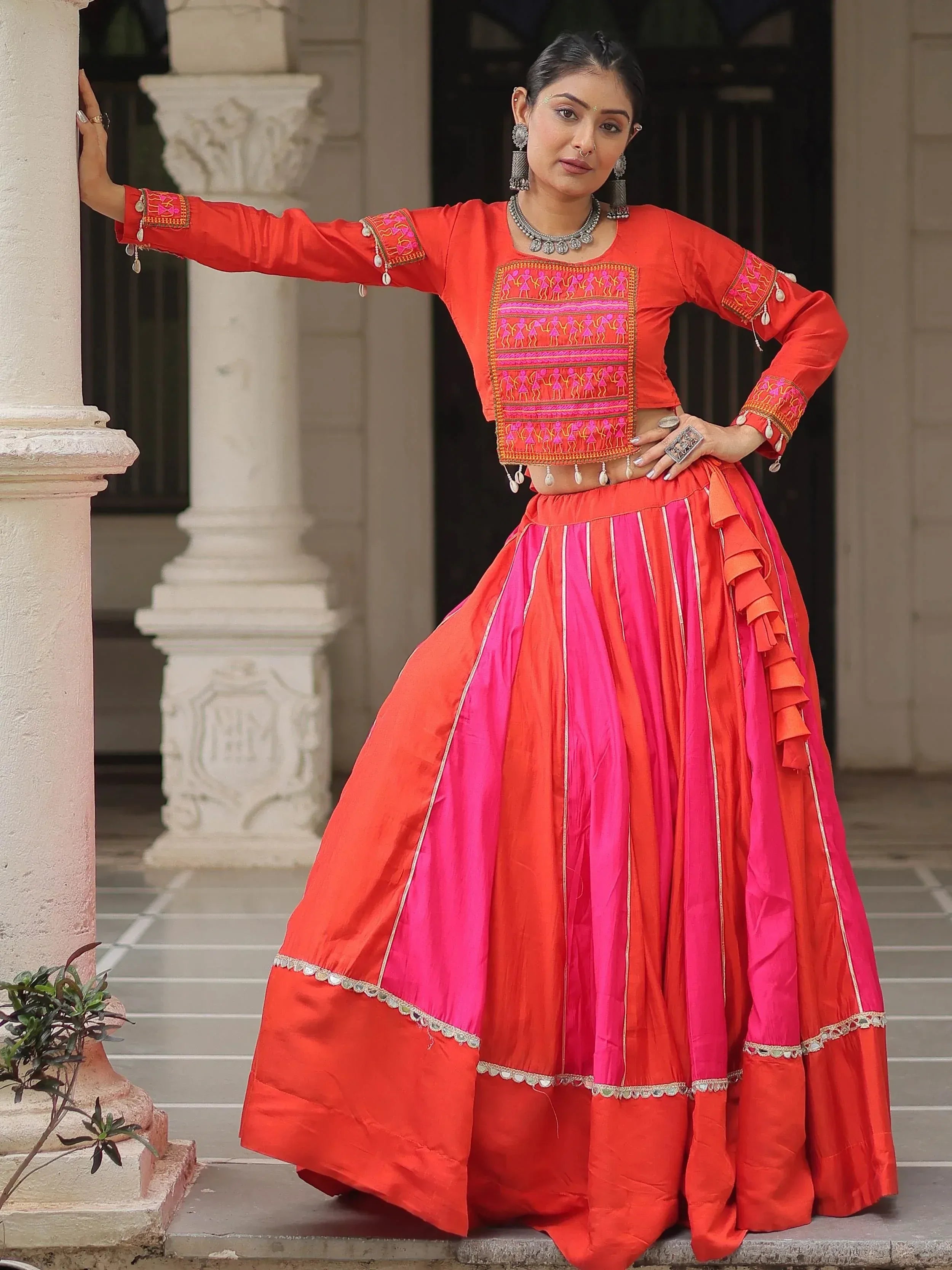 Vibrant red and pink ethnic lehenga choli with embroidered blouse and ruffled skirt, perfect for festive occasions.